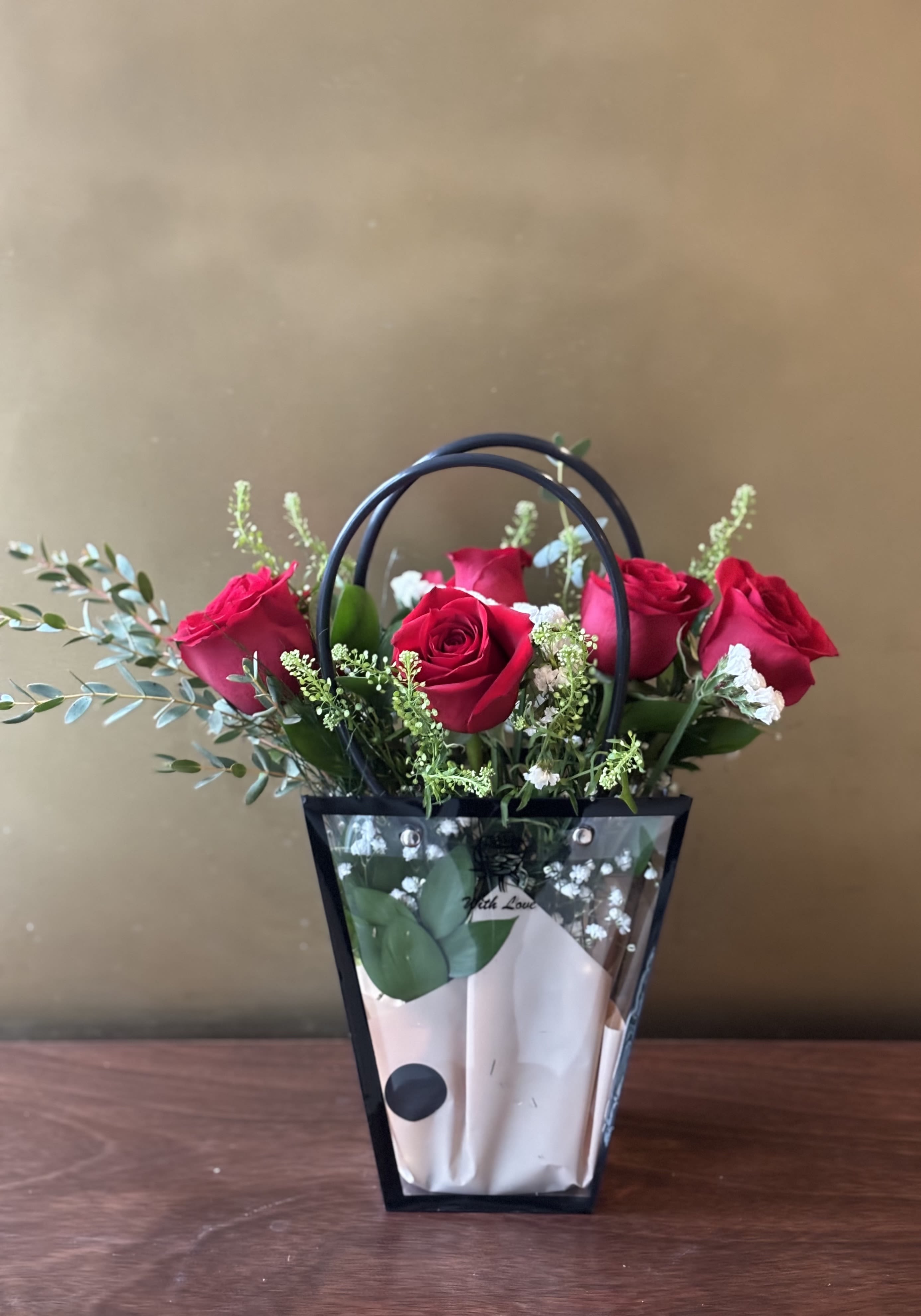 Bouquet of red roses in a black handled gift bag