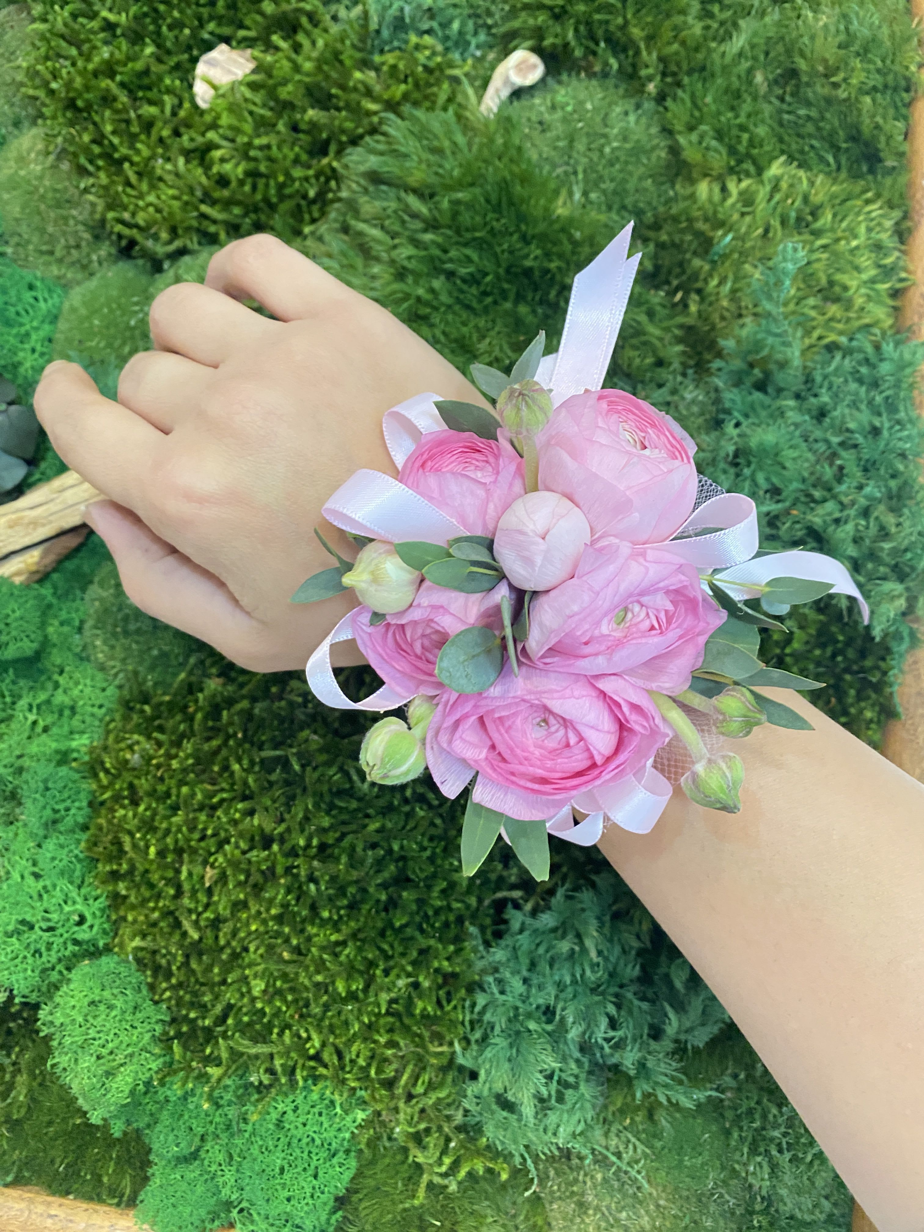 Pink floral wrist corsage with ribbon on a person's wrist
