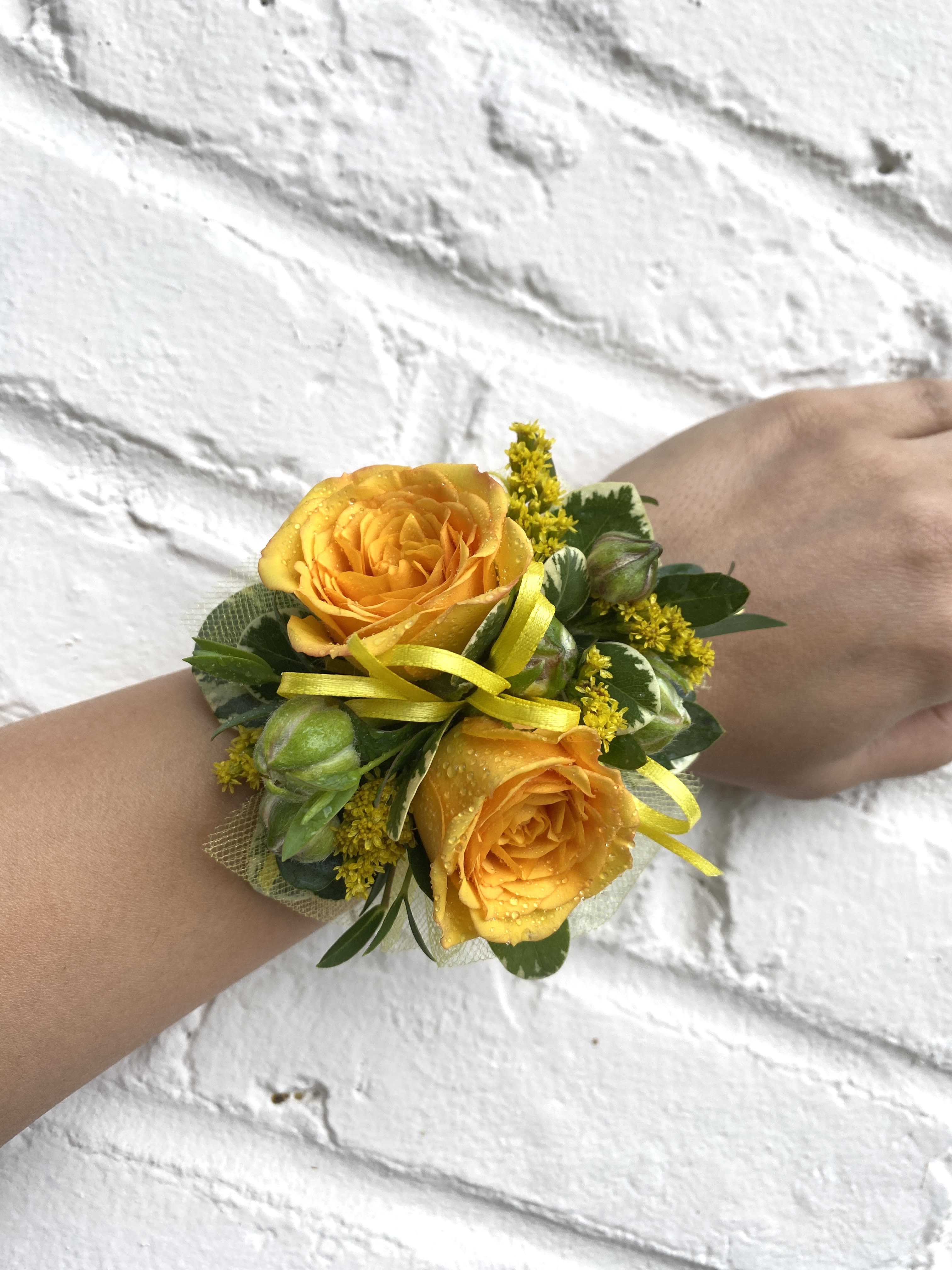 Yellow rose wrist corsage with ribbon and greenery