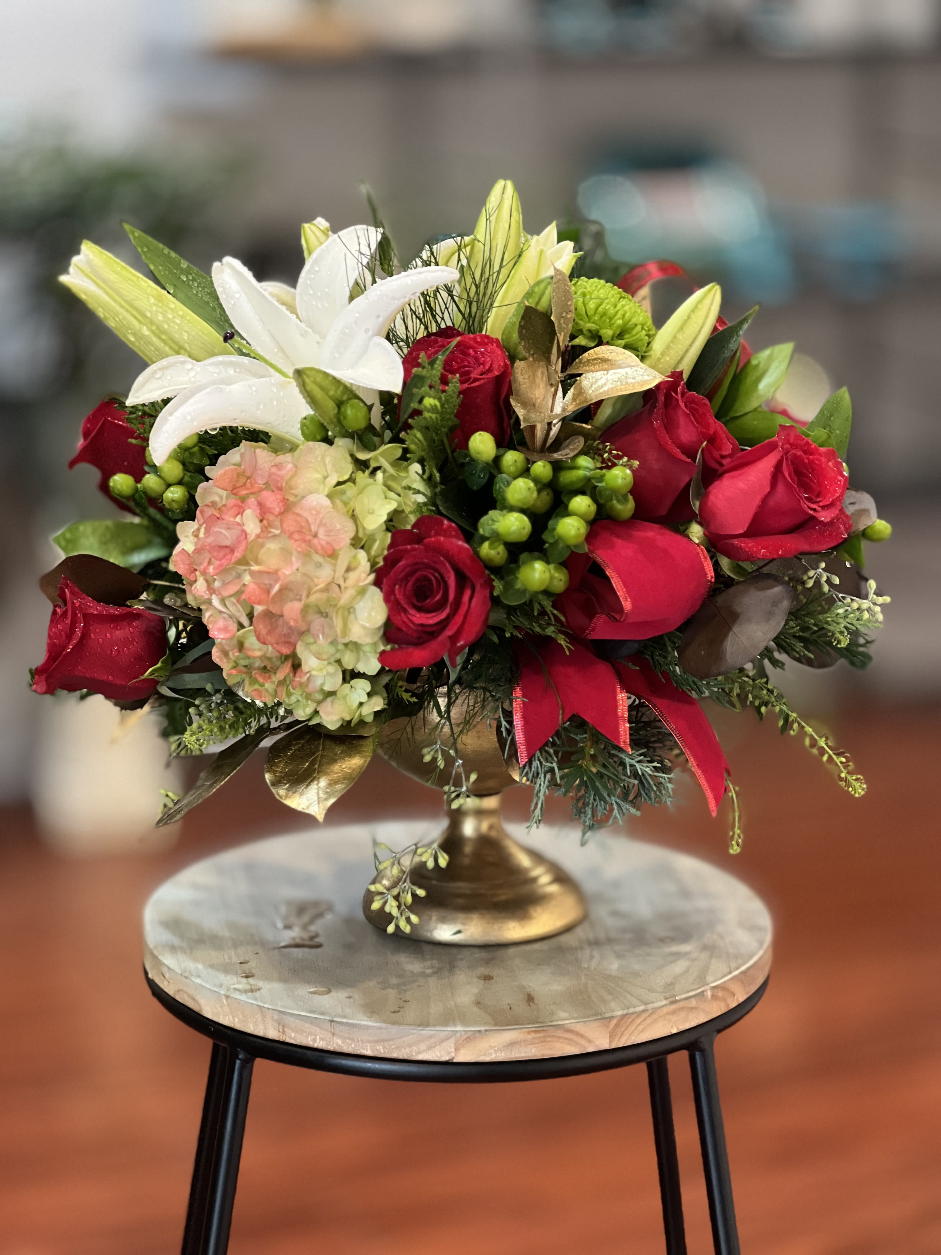 Red roses and white lilies arranged in a gold pedestal vase