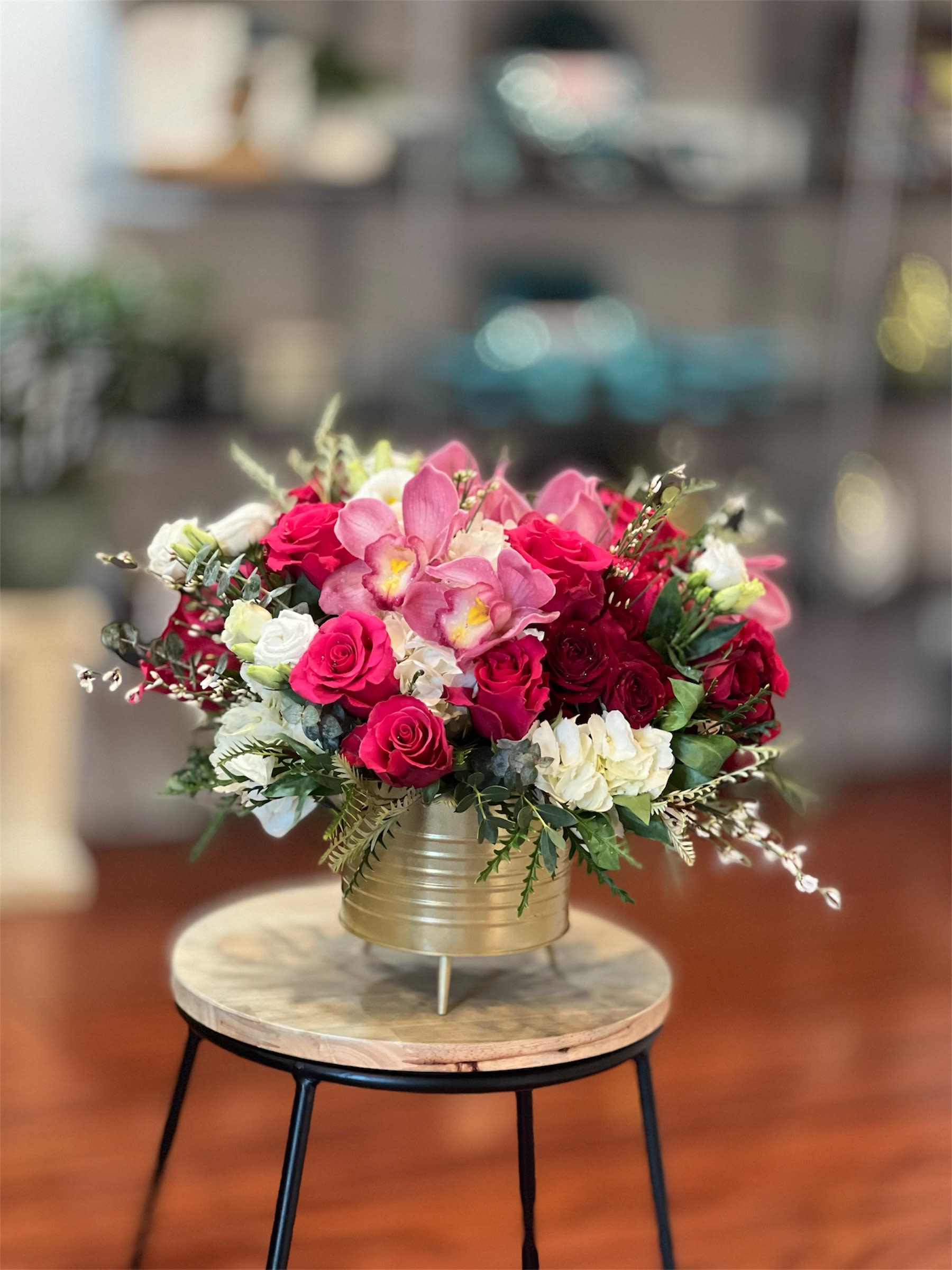 Pink and red rose bouquet in a gold vase on a small table