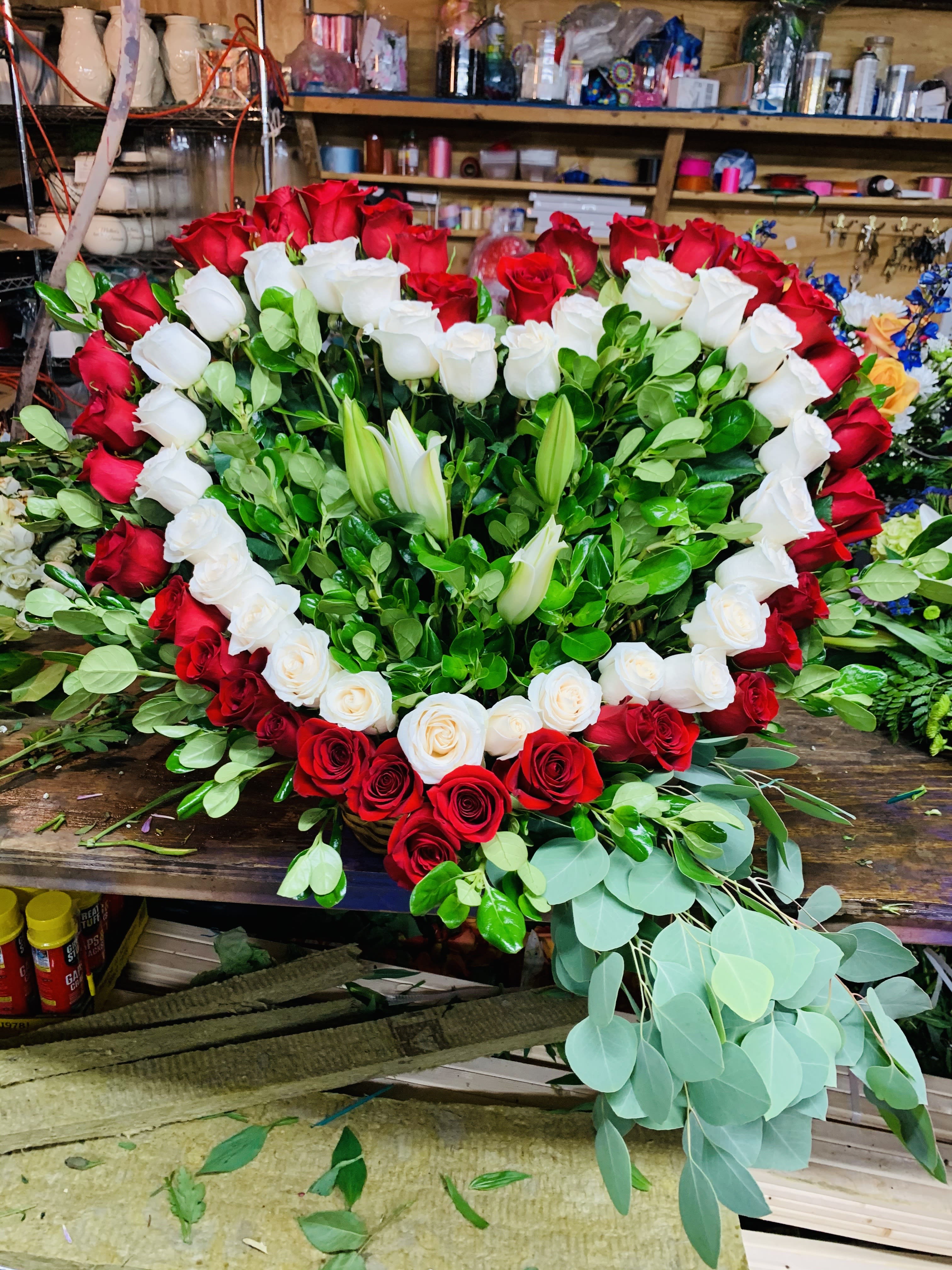 Heart-shaped red and white rose arrangement with lilies and greenery