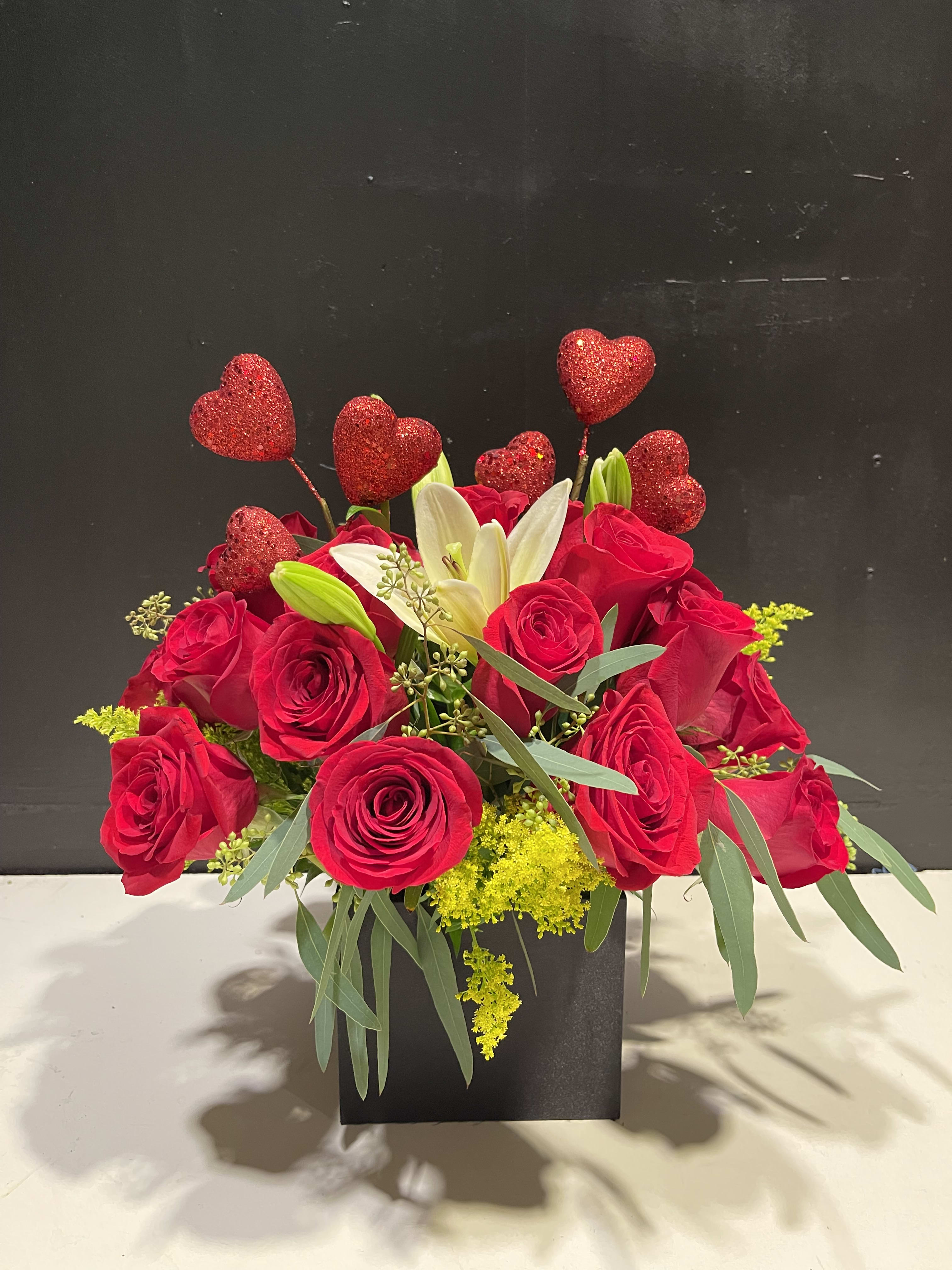 Red roses and white lilies in a black box with glitter heart picks