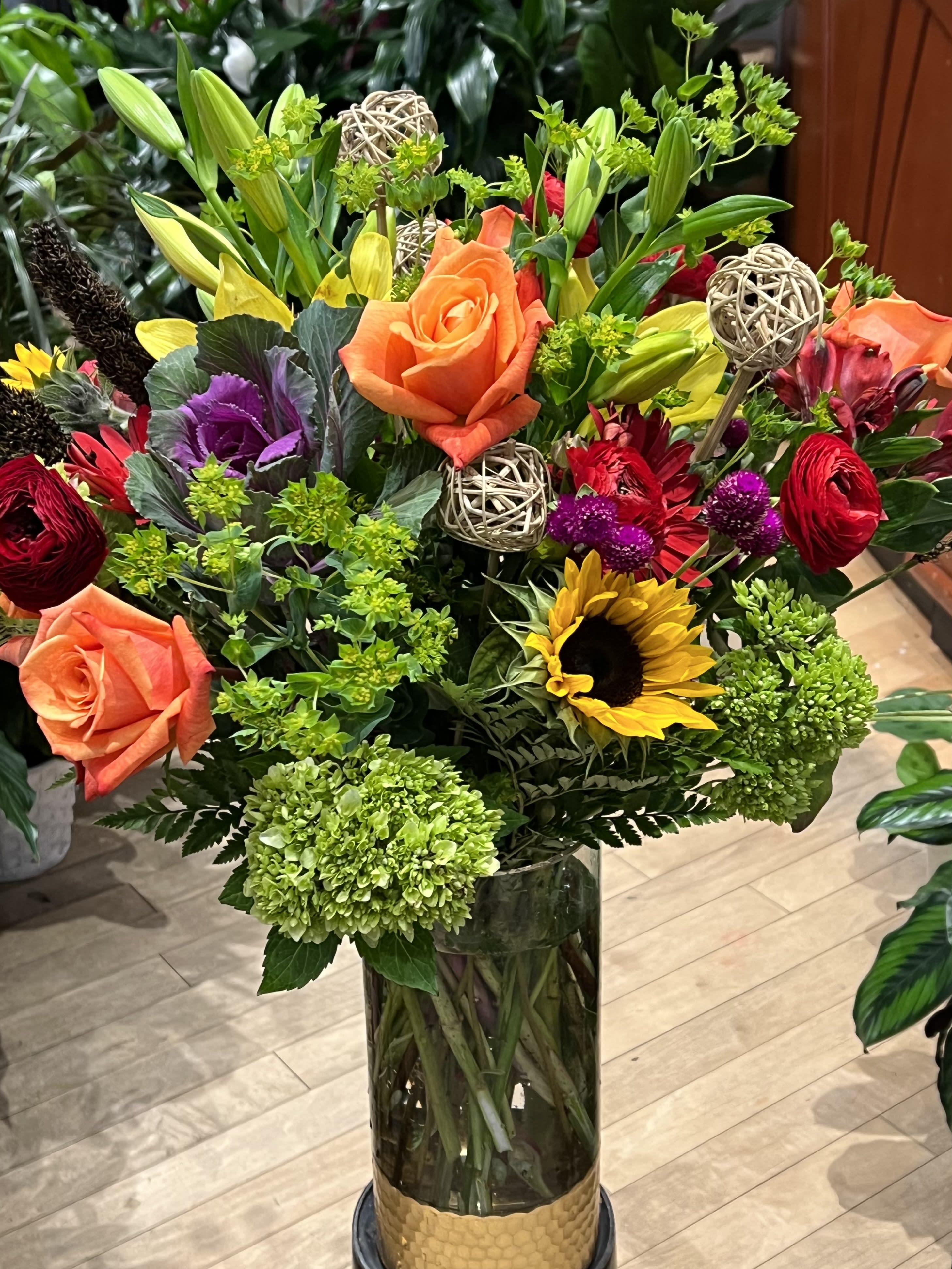 Mixed bouquet with roses, lilies, sunflowers, and hydrangeas in a glass vase