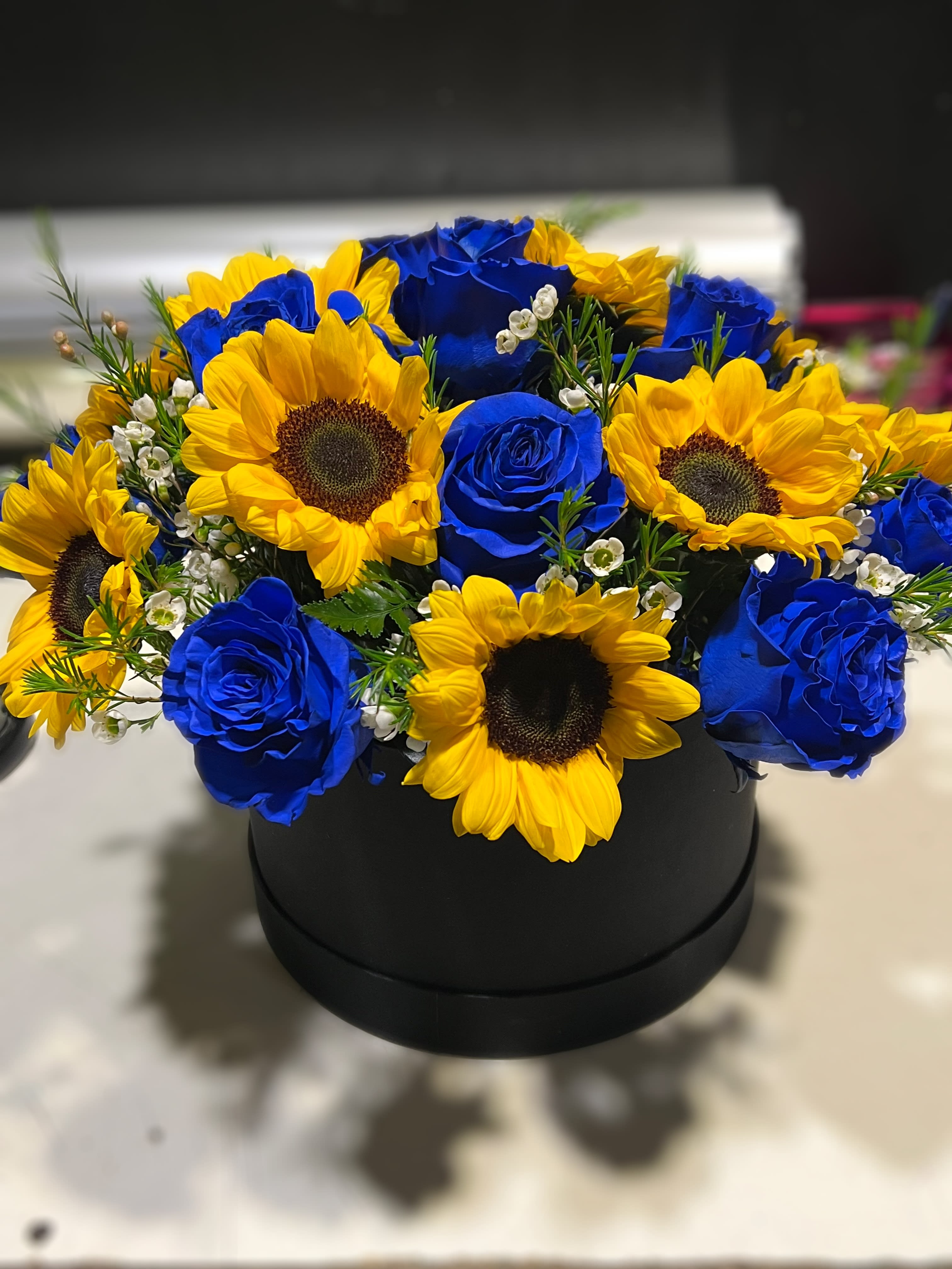 Midnight petals - Delicate floral arrangement with blue roses that contrast like a starry night with the brightness of the sunflowers.