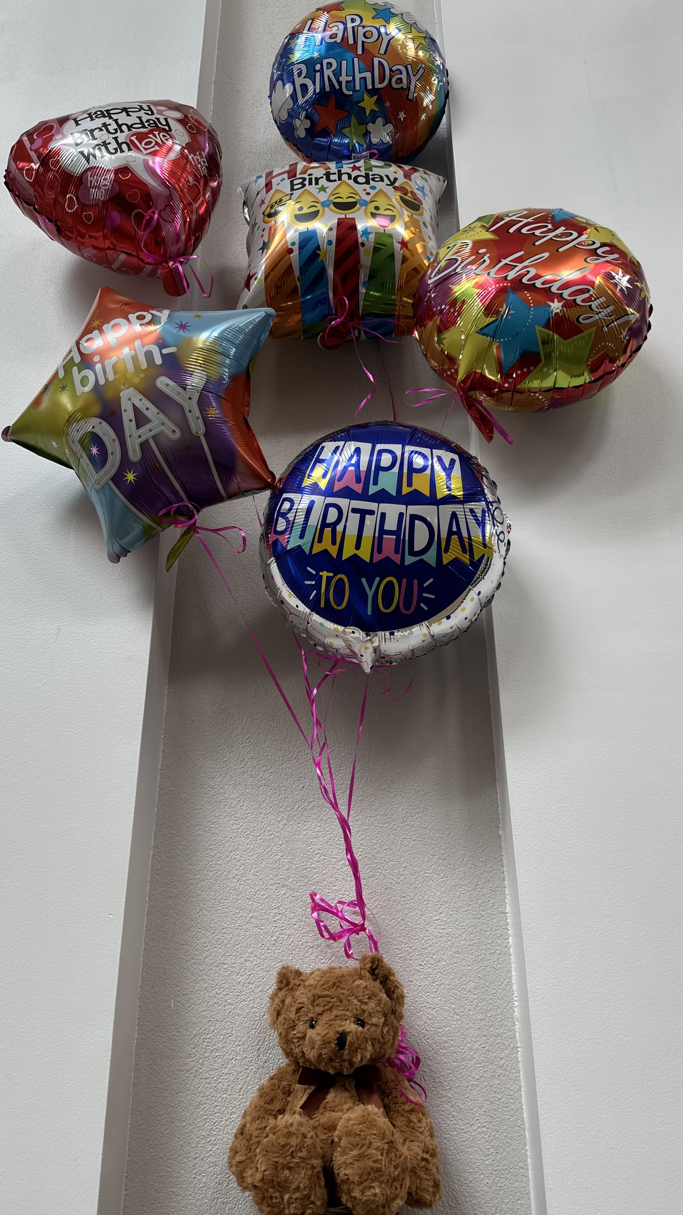 Birthday balloons tied to a teddy bear