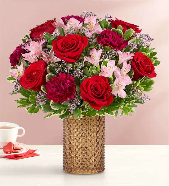 Red roses and pink flowers arranged in a textured vase