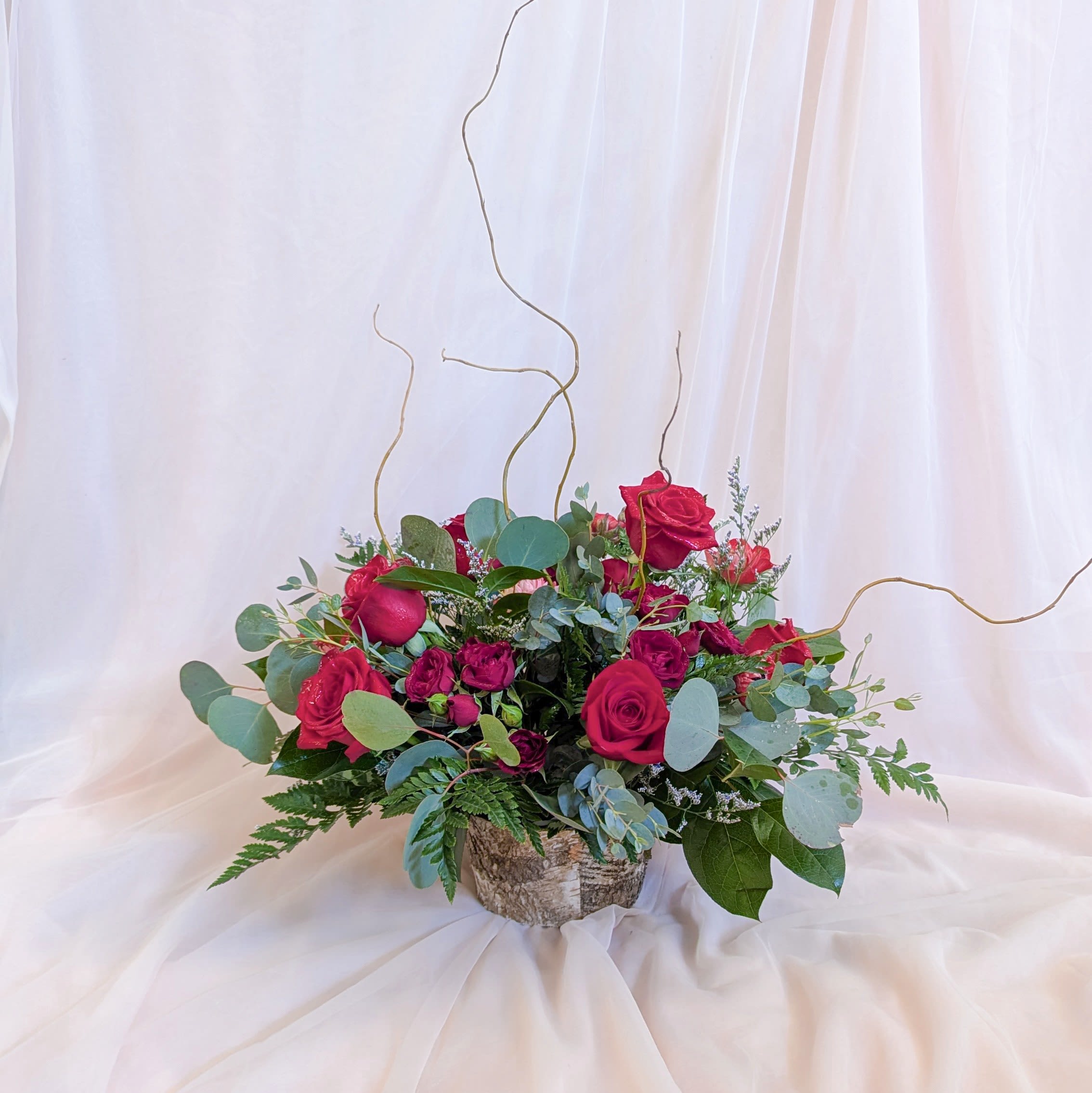 Red roses in a rustic birch container with eucalyptus