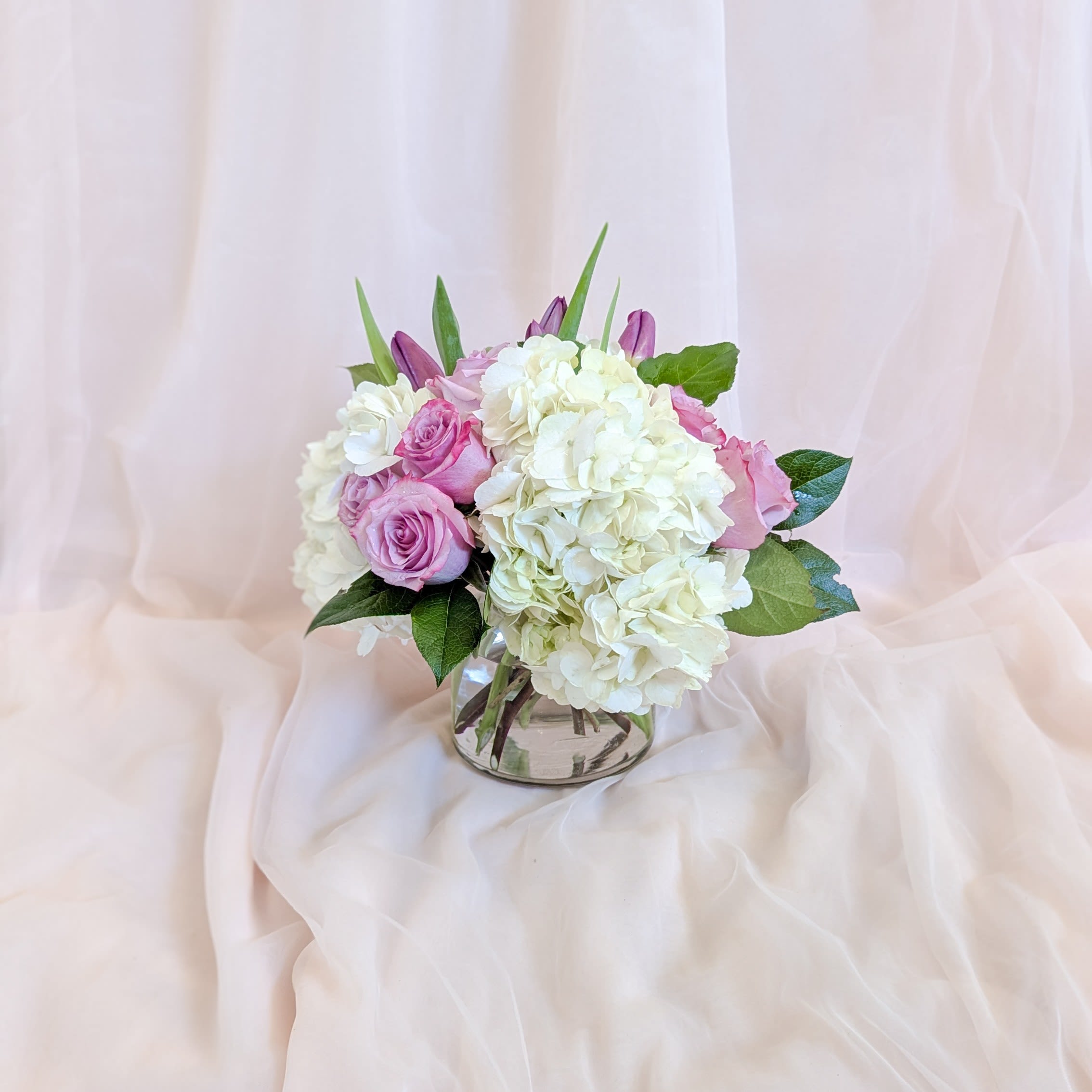 Pink roses and white hydrangeas arranged in a clear glass vase