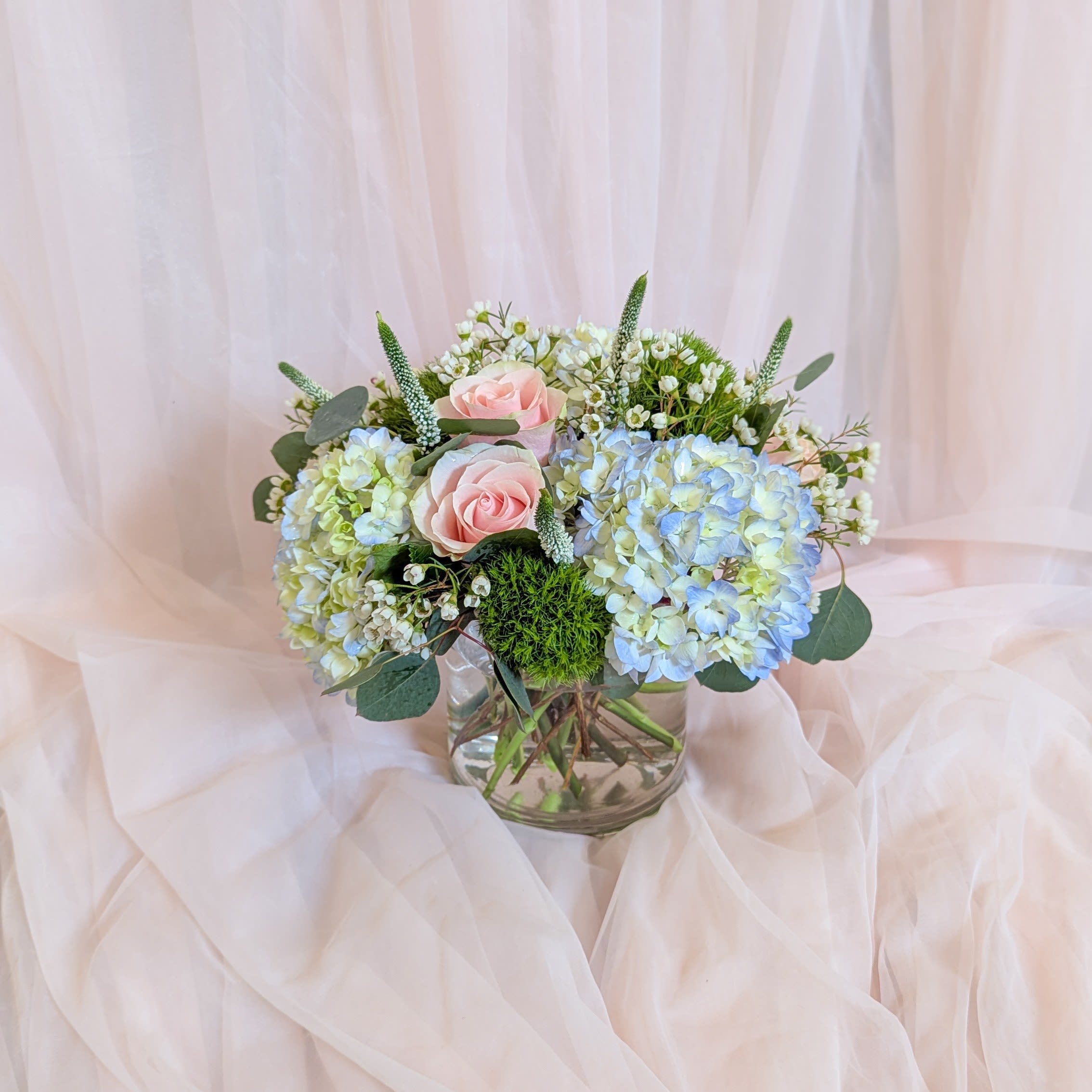 Pink roses and blue hydrangeas in a glass vase