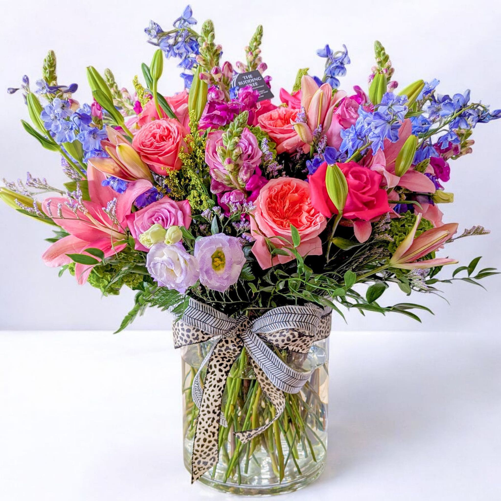 Colorful mixed bouquet in a clear glass vase with a patterned ribbon