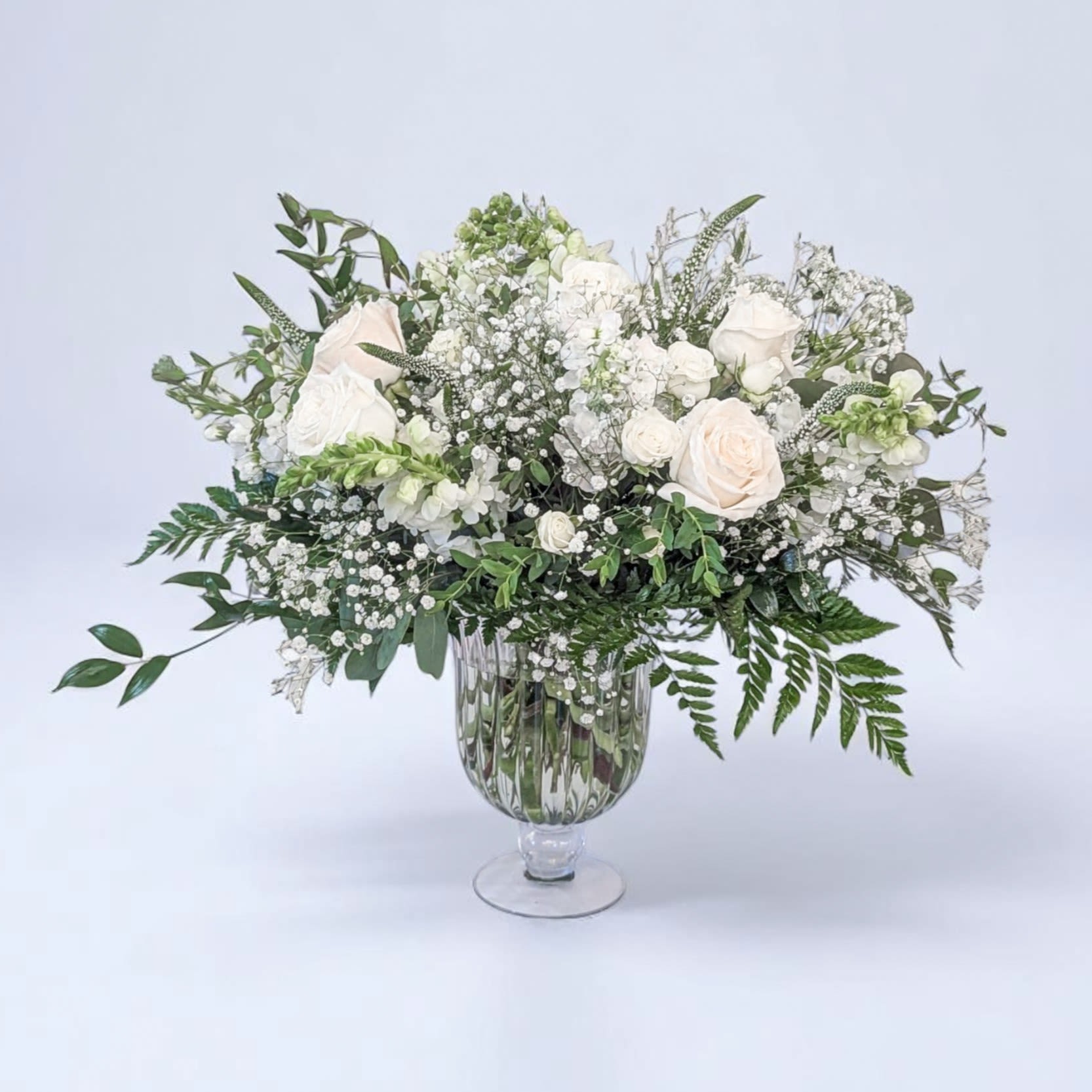 White roses and baby's breath in a clear glass vase