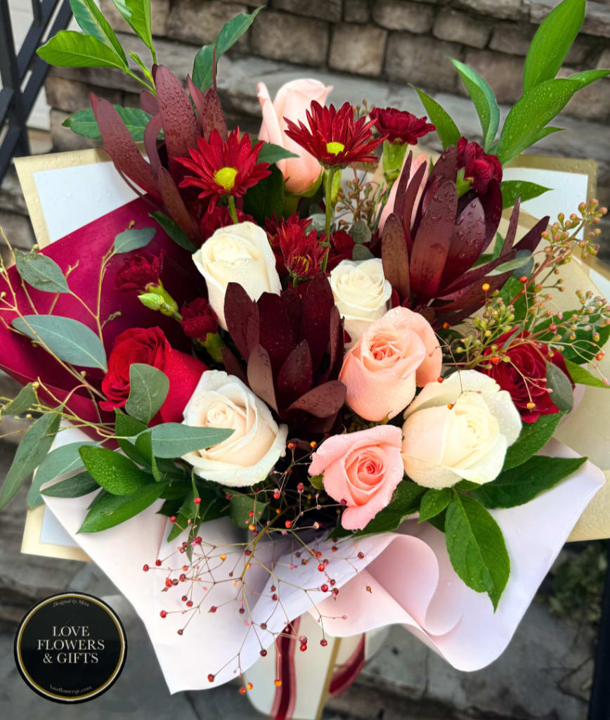 Bouquet of red, pink, and white roses with burgundy flowers and greenery