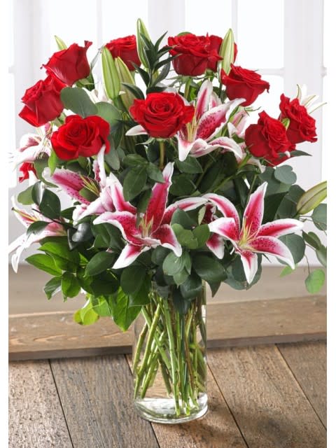 Red roses and pink stargazer lilies in a clear glass vase