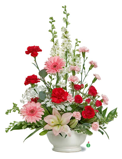 Pink and red mixed flower arrangement in a white vase