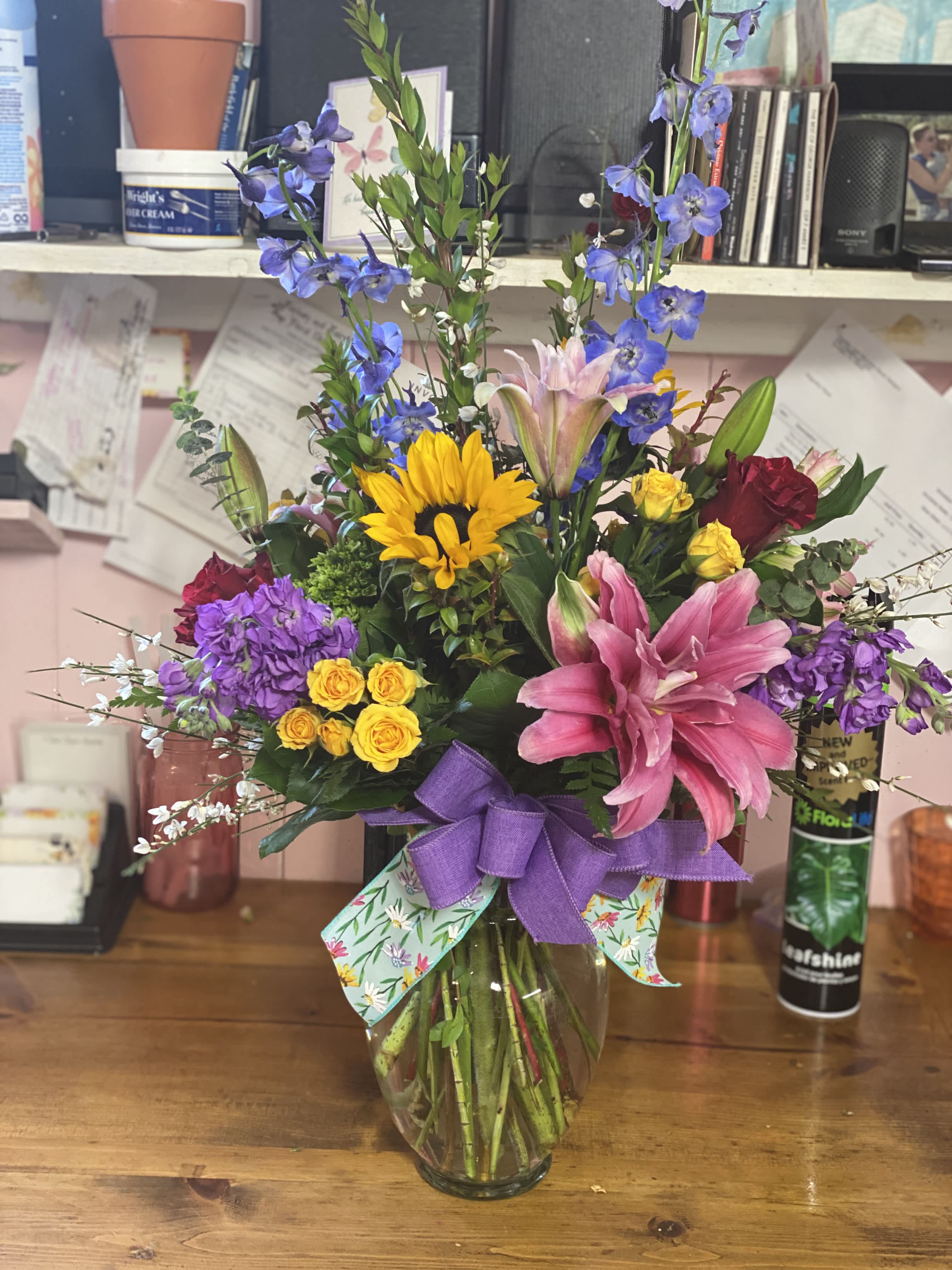 Colorful mixed bouquet in a glass vase with a purple ribbon