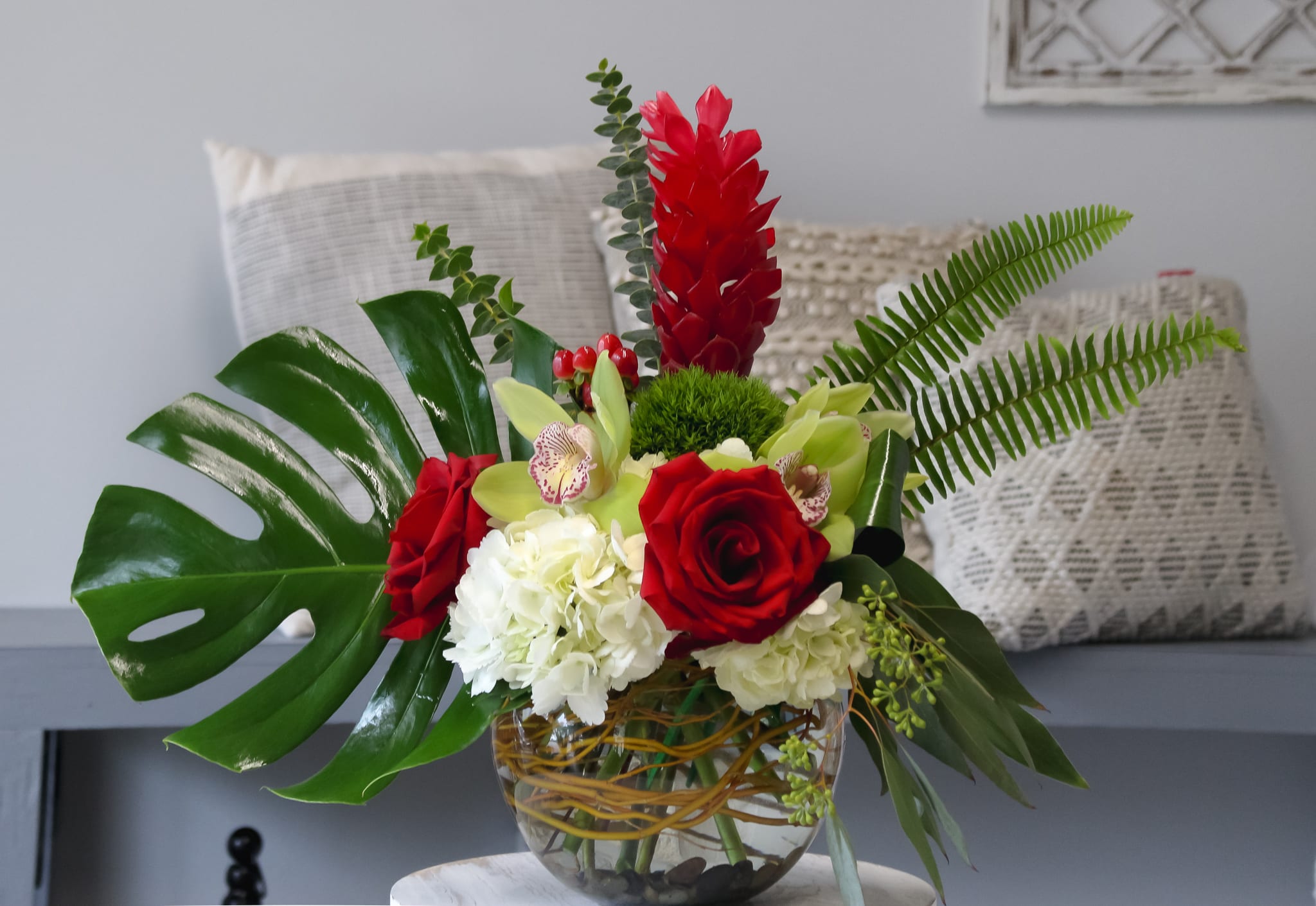 Tropical floral arrangement with red roses and white hydrangeas in a glass vase