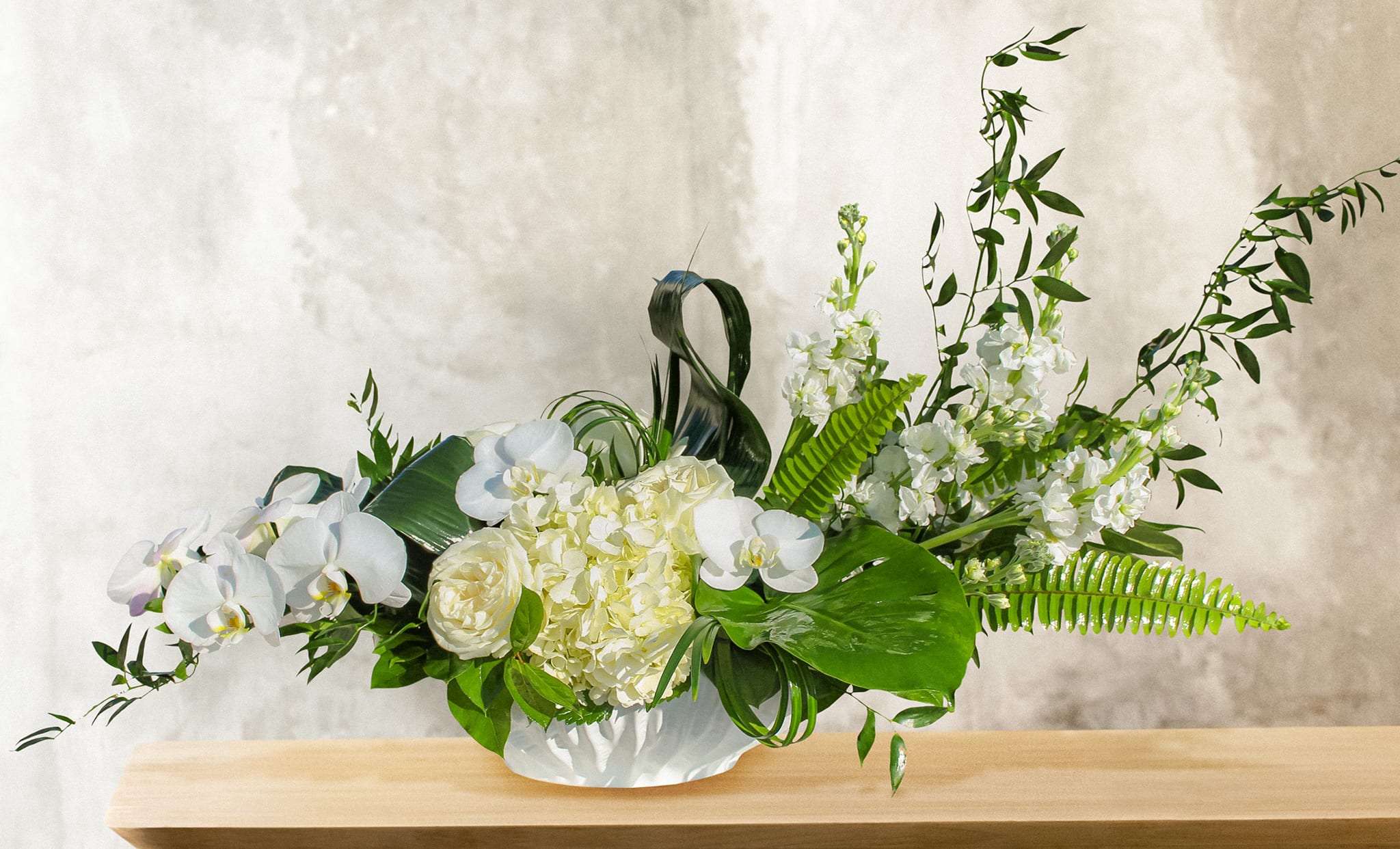 White orchid and hydrangea arrangement in a low white vase