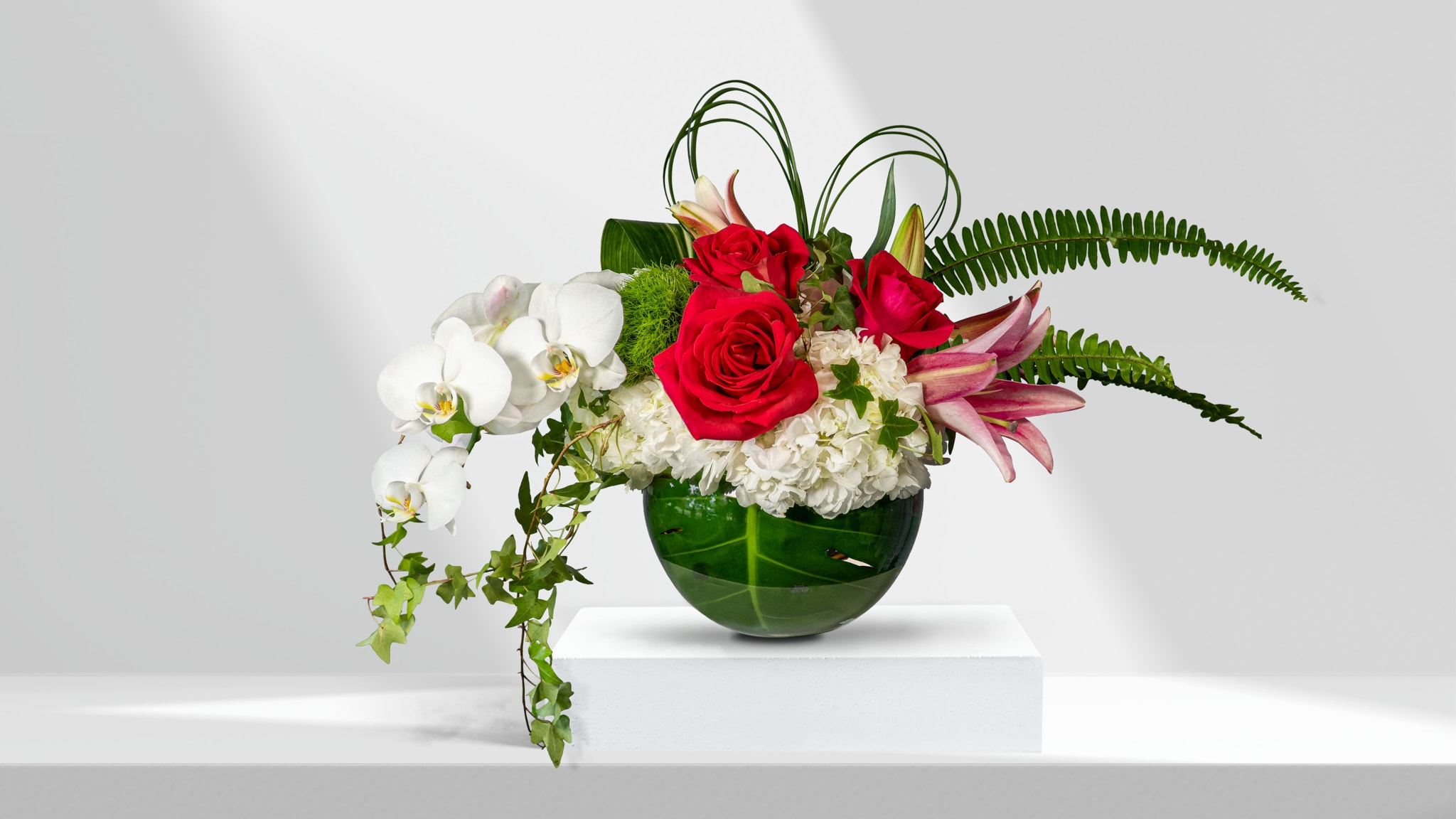 Red roses and white orchids in a green glass vase