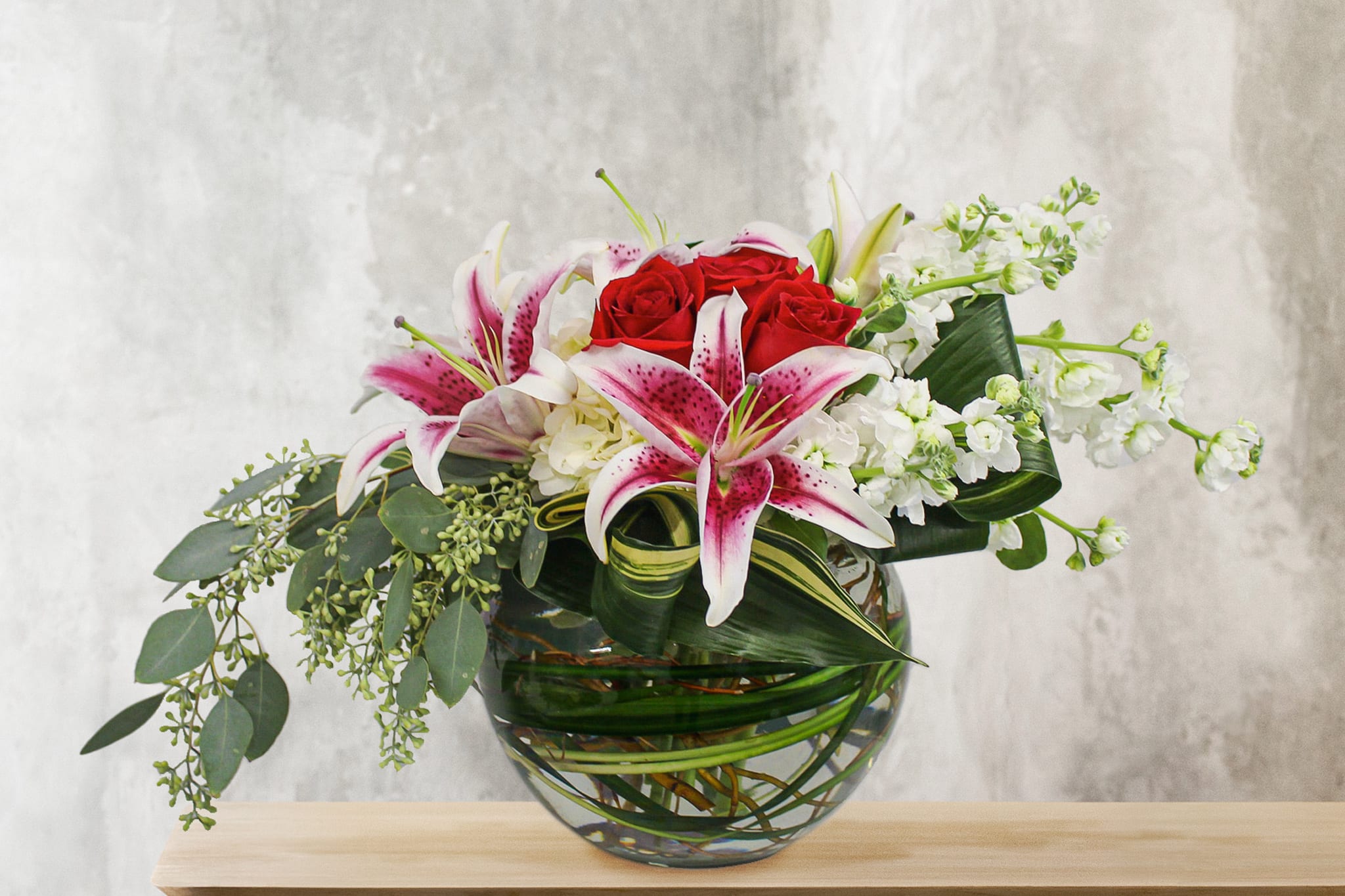 Bouquet of red roses and pink lilies in a glass vase