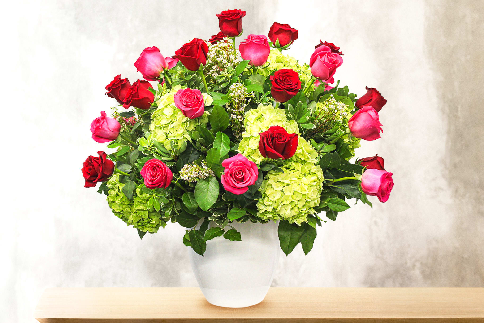 Bouquet of red and pink roses with green hydrangeas in a white vase