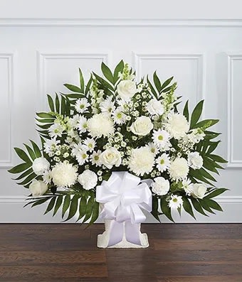 White floral standing spray with a large bow on a white easel