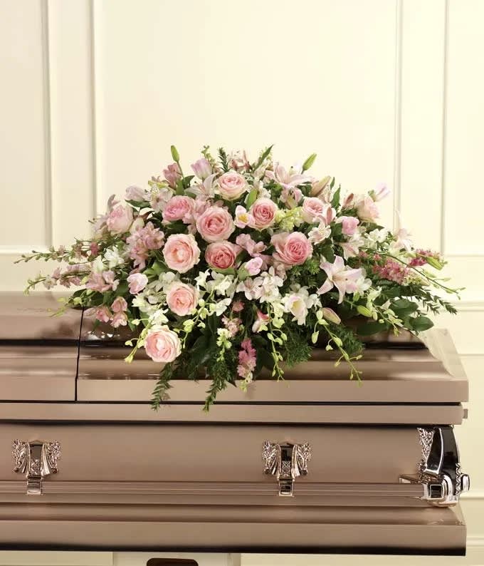 Pink and white floral casket spray on a beige casket