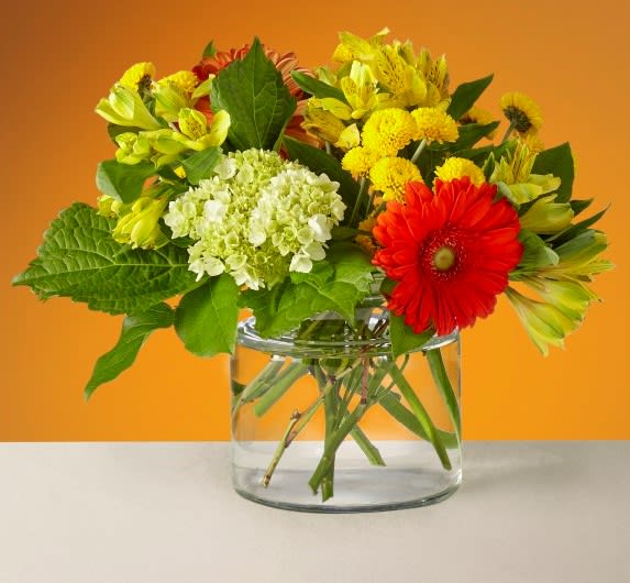 Mixed bouquet of yellow, red, and white flowers in a clear glass vase