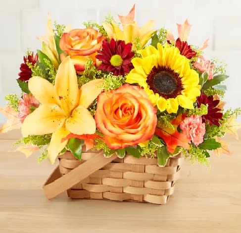 Basket arrangement with yellow lilies, orange roses, and a sunflower