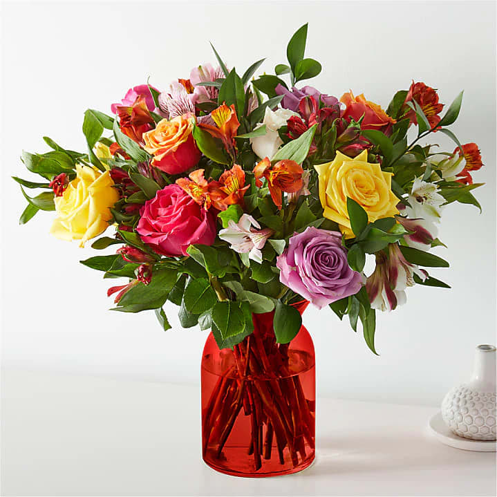 Mixed bouquet of roses and alstroemeria in a red glass vase