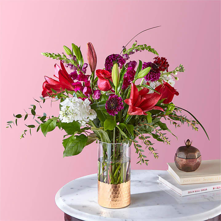 Mixed bouquet of red and purple flowers in a clear glass vase