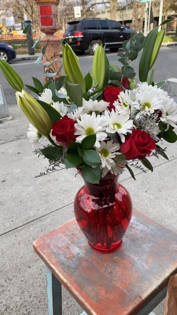 Red roses and white daisies in a red glass vase