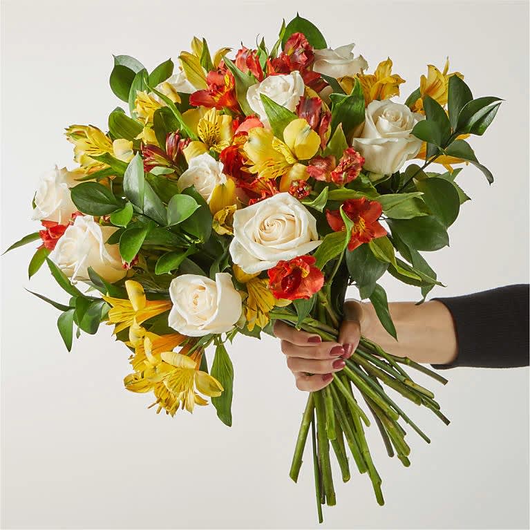 Handheld bouquet of white roses and yellow-red alstroemeria