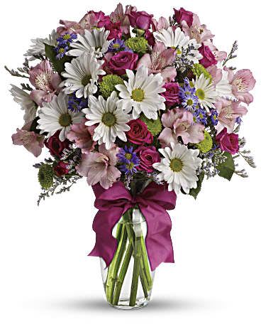 Bouquet of pink and white flowers in a glass vase with a magenta ribbon