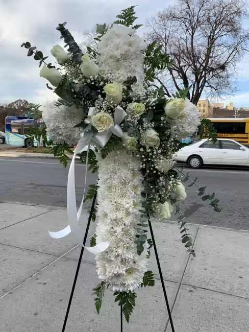 Tall white floral standing spray on an easel with ribbon