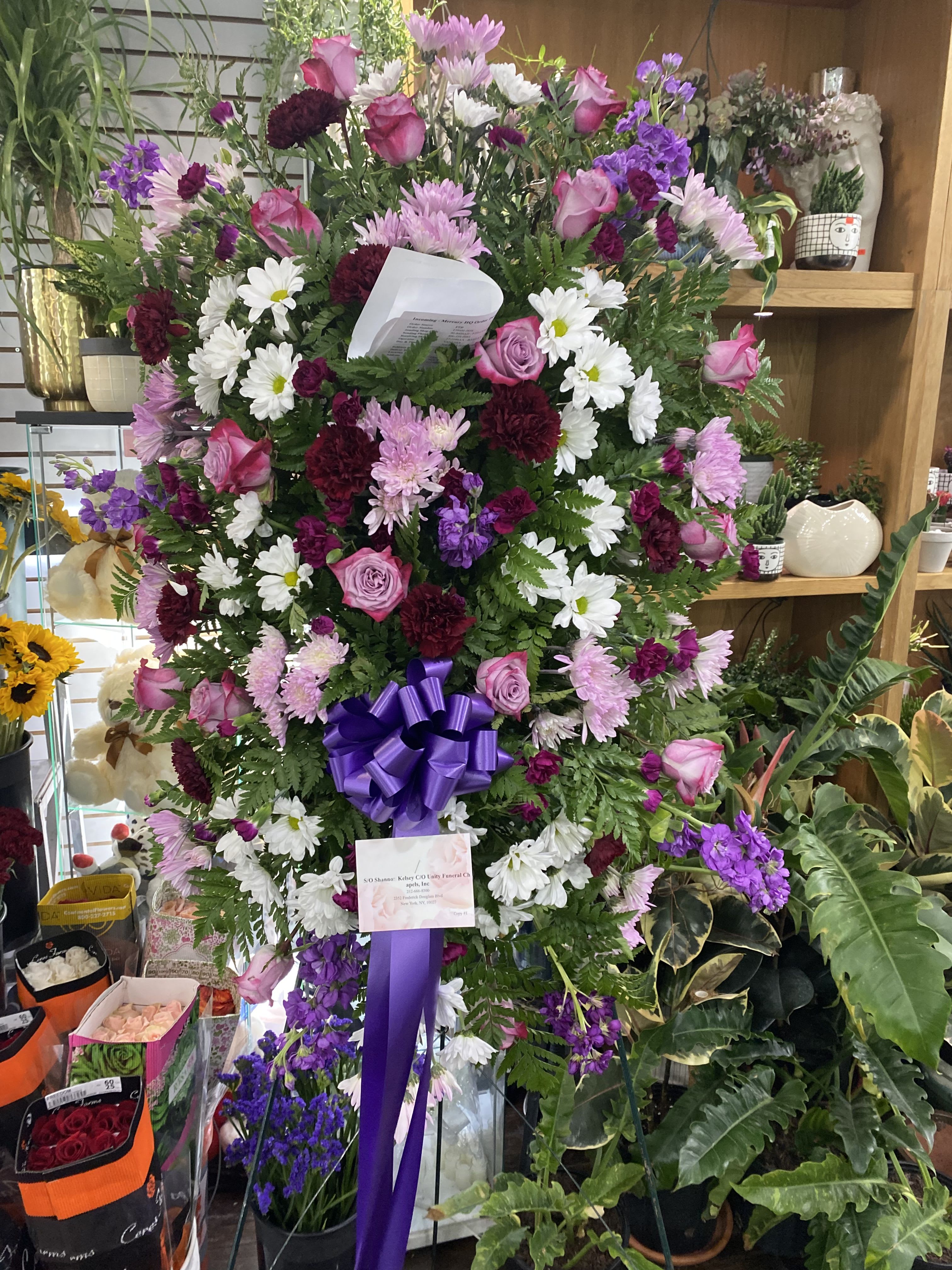 Large standing spray of pink, white, and purple flowers with a purple ribbon