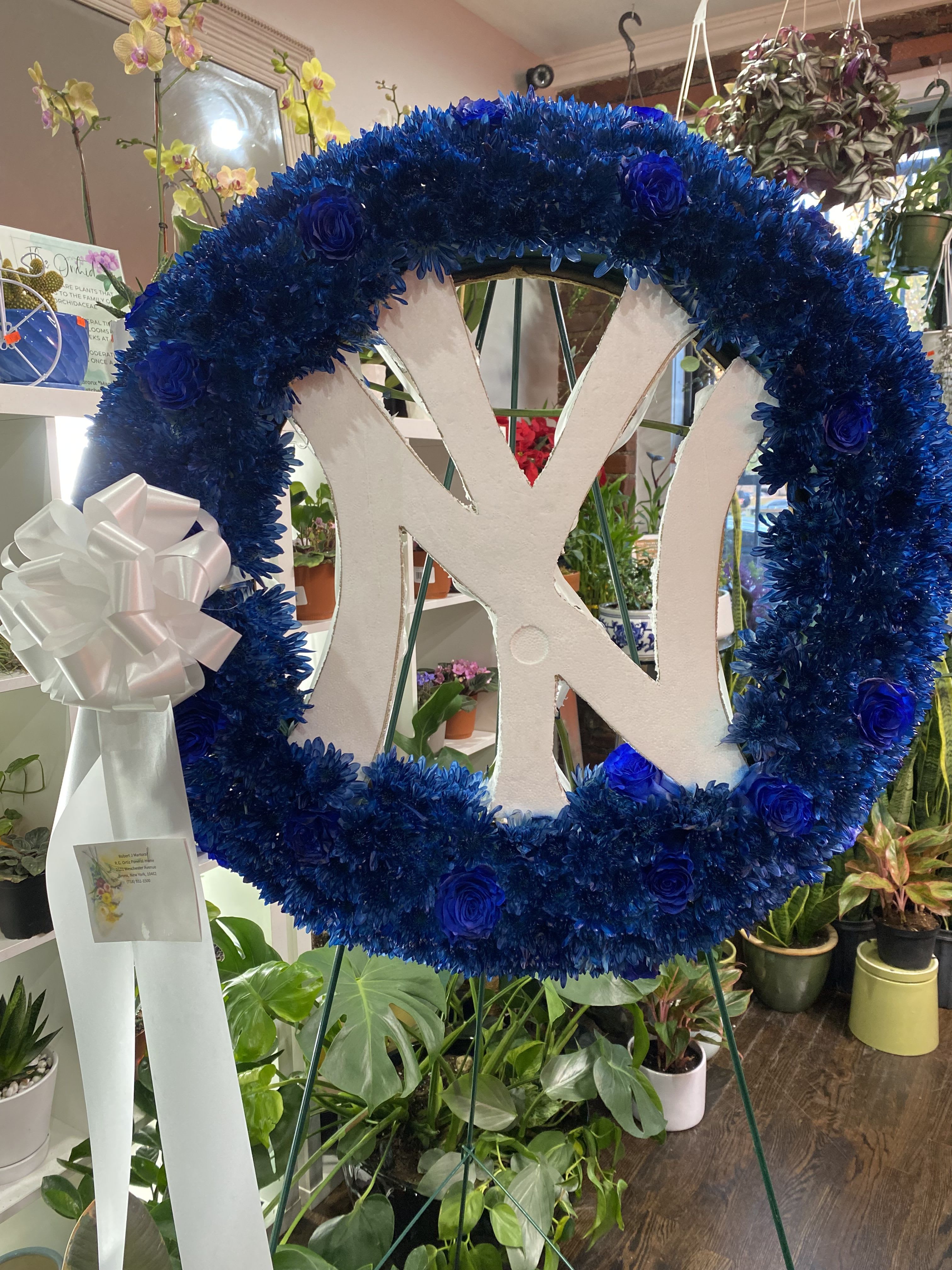 Blue floral wreath with a white monogram and ribbon bow on an easel