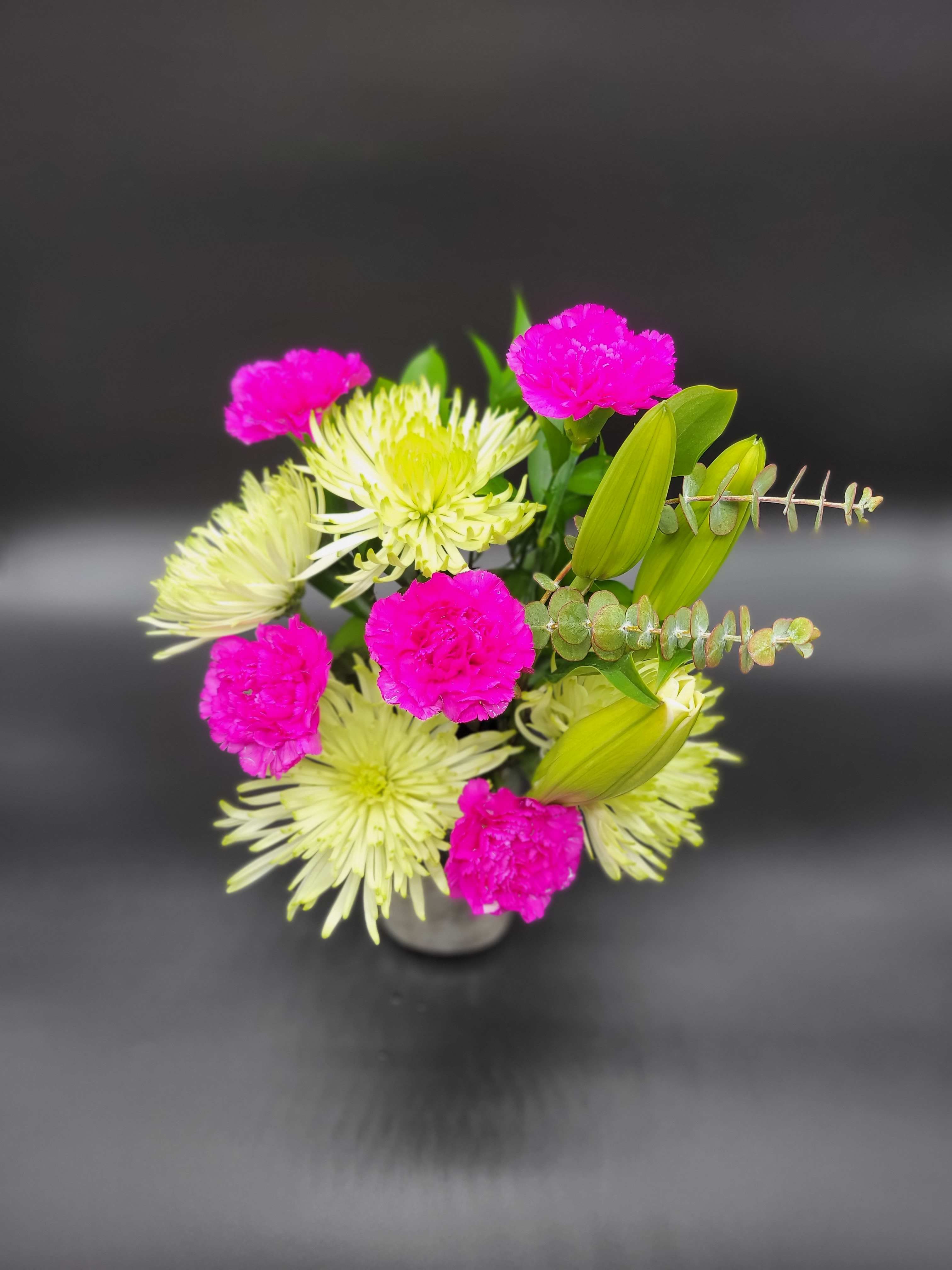 Pink carnations and pale green spider mums in a small vase