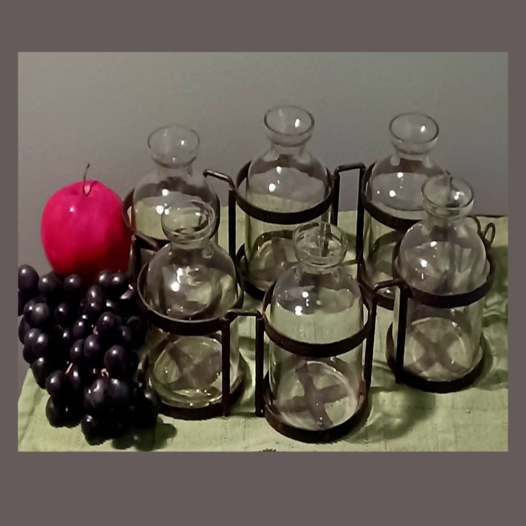 Glass bottles and a red candle beside a bunch of dark grapes