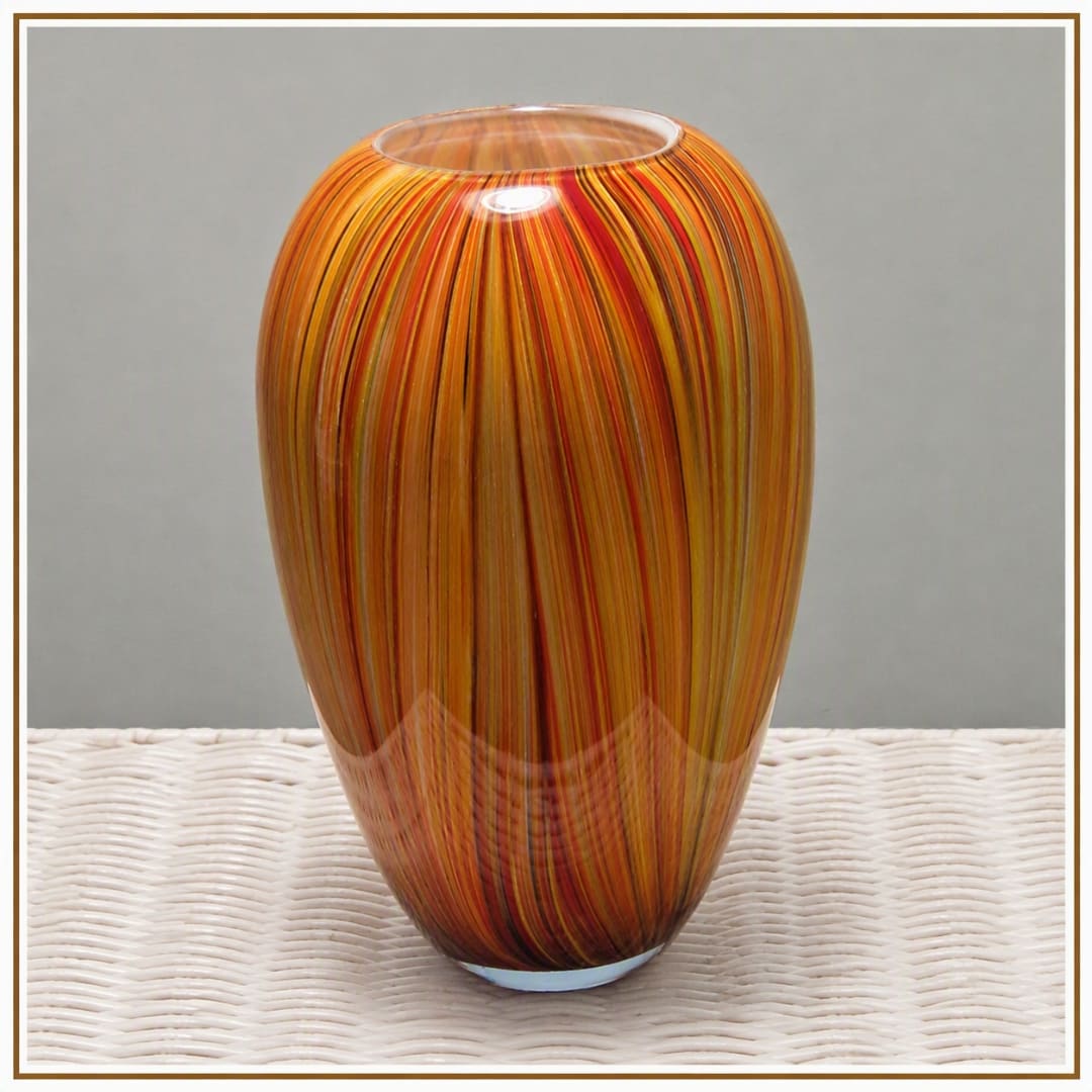 Orange striped glass vase on a woven surface