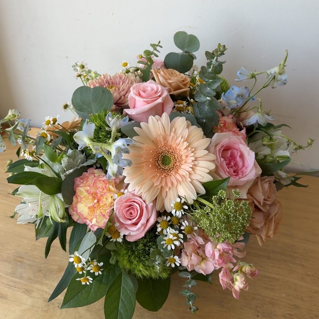 Mixed bouquet with pink roses, a peach gerbera daisy, and blue flowers