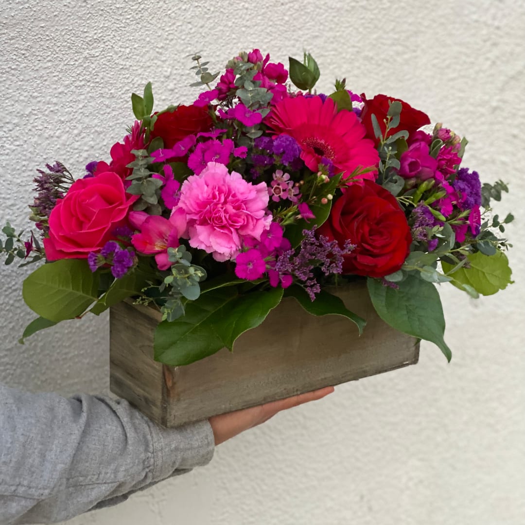 Pink and red mixed flower arrangement in a wooden box