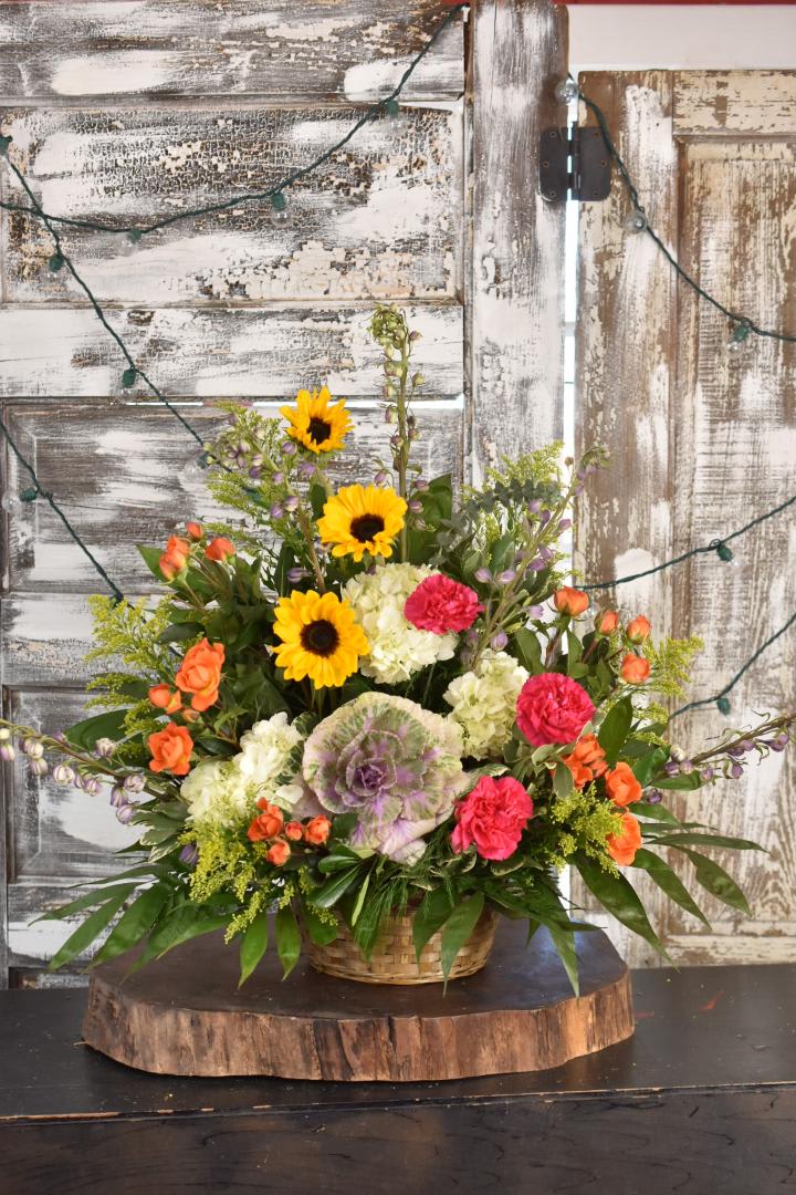 Mixed bouquet in a wicker basket with sunflowers, carnations, and hydrangeas