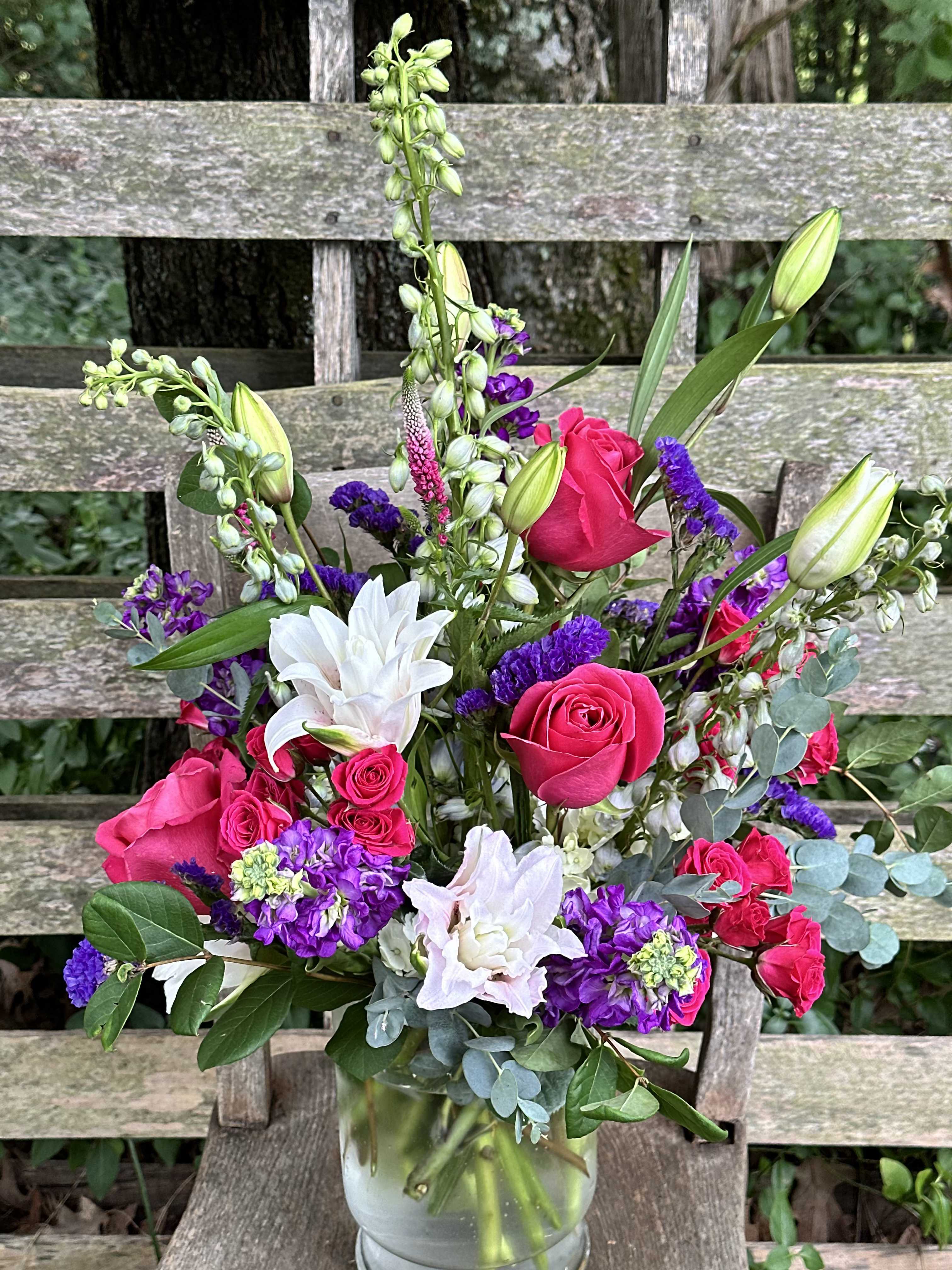 Make Plans - Bright pink roses and stargazer lilies come together with purple stock and greenery for this impressive arrangement.   