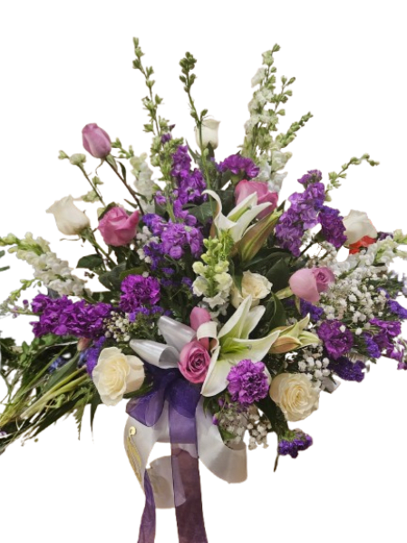 Graceful Garden Tribute - A timeless expression of love and remembrance, Graceful Garden Tribute is designed with a soft, elegant garden style that brings comfort and beauty to any service. This arrangement features a delicate blend of lavender, soft pink, and creamy white blooms—including lilies, roses, and seasonal florals—thoughtfully arranged with lush greenery and gentle movement.  The soothing color palette and natural, flowing design create a sense of peace and grace, offering a heartfelt way to honor and celebrate a cherished life. Each bloom is carefully selected to symbolize love, remembrance, and enduring connection. Personalized Ribbon add $10.00