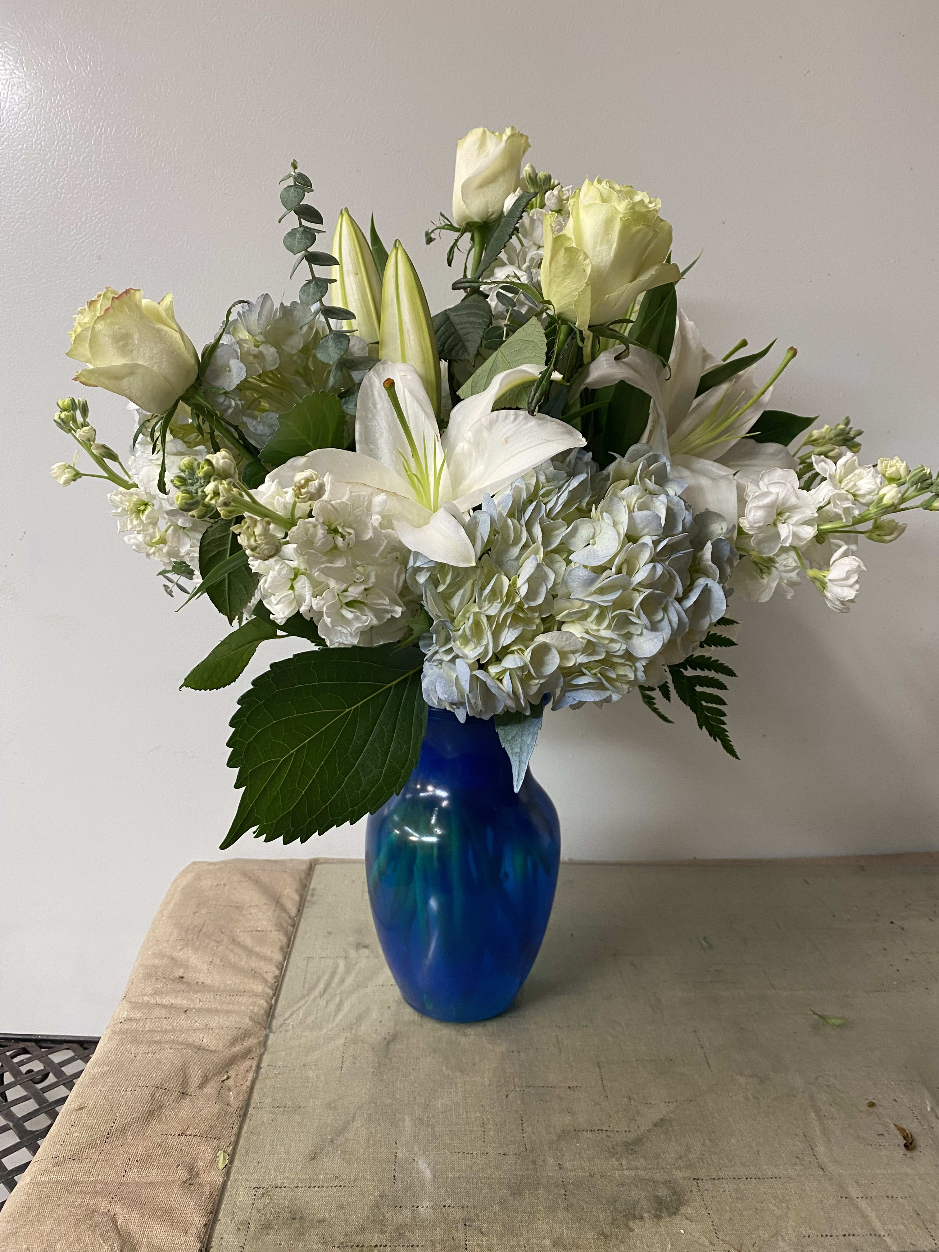 White roses and lilies arranged in a blue vase