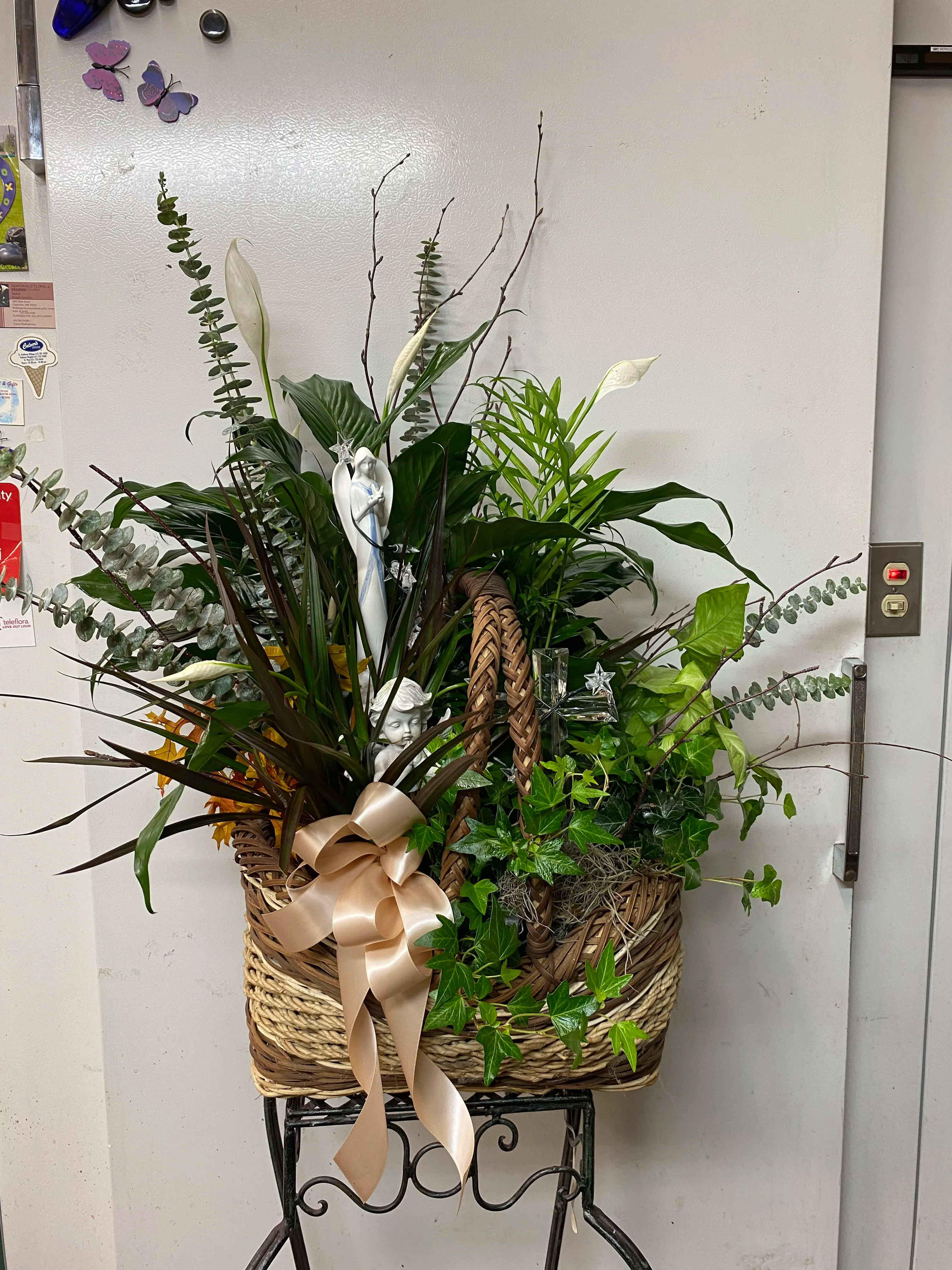 Basket arrangement with white calla lilies, greenery, and a satin bow