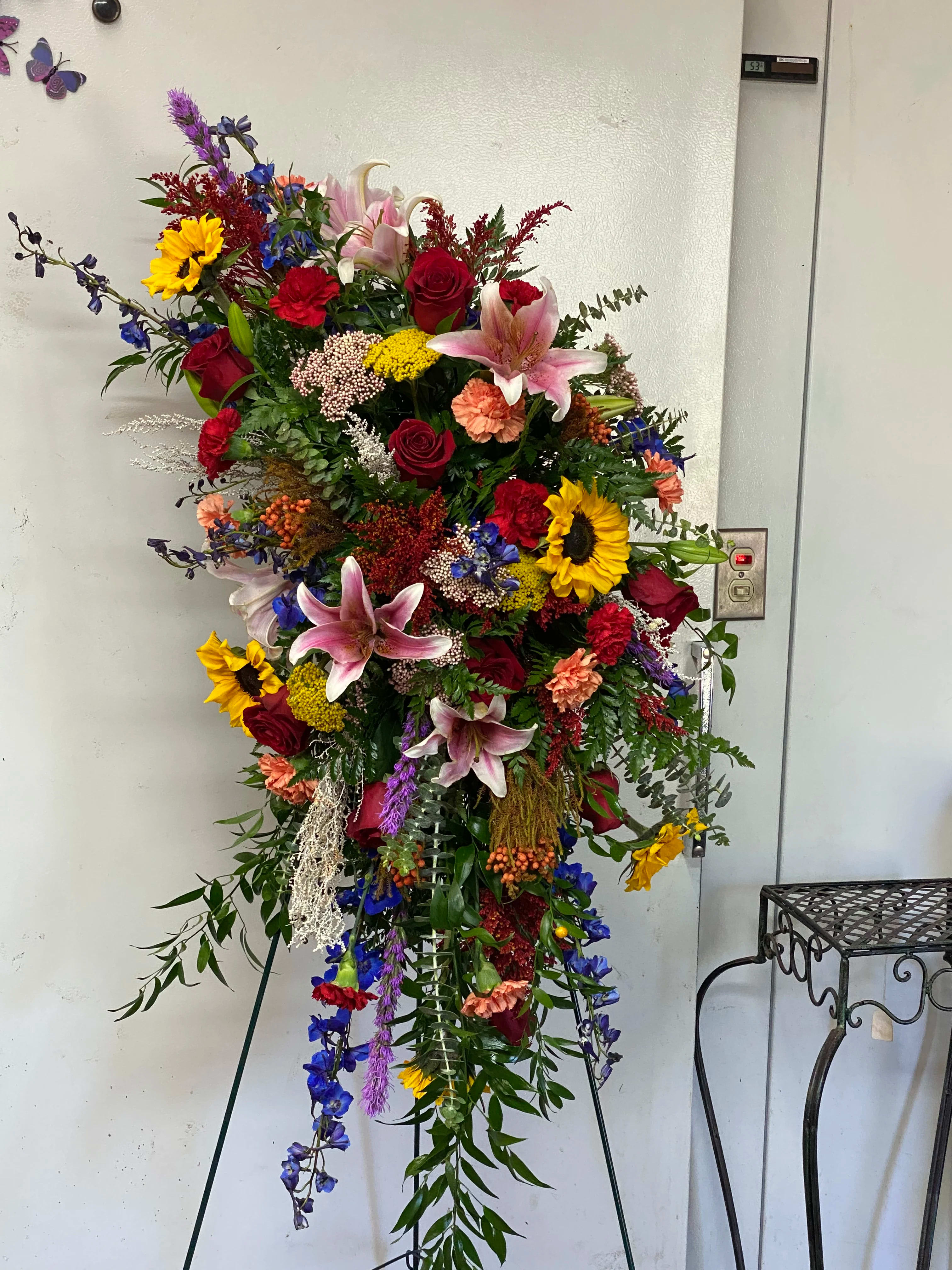 Tall standing floral spray with roses, lilies, and sunflowers