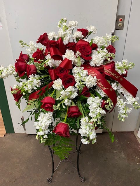 Standing floral spray of red roses and white flowers with red ribbons