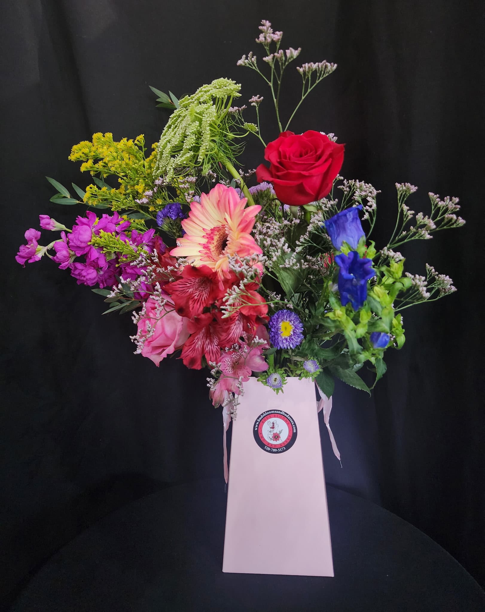 Mixed bouquet in a pink gift box with red, pink, purple, and blue flowers